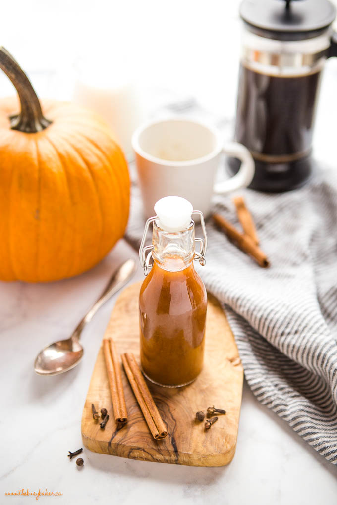 glass bottle of pumpkin spice coffee syrup with cinnamon sticks