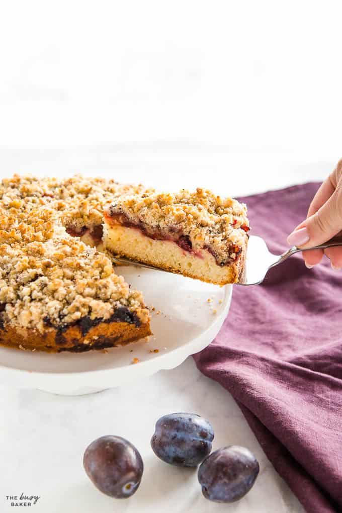 hand serving a slice of yogurt plum cake