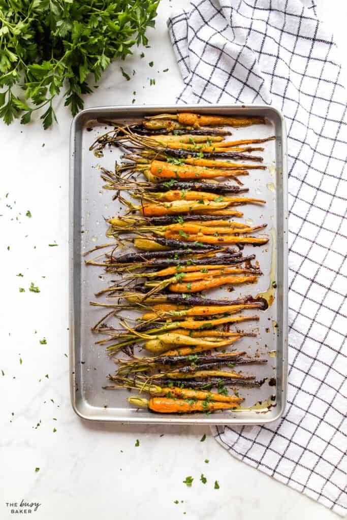 orange white and purple carrots roasted on sheet pan with tops attached