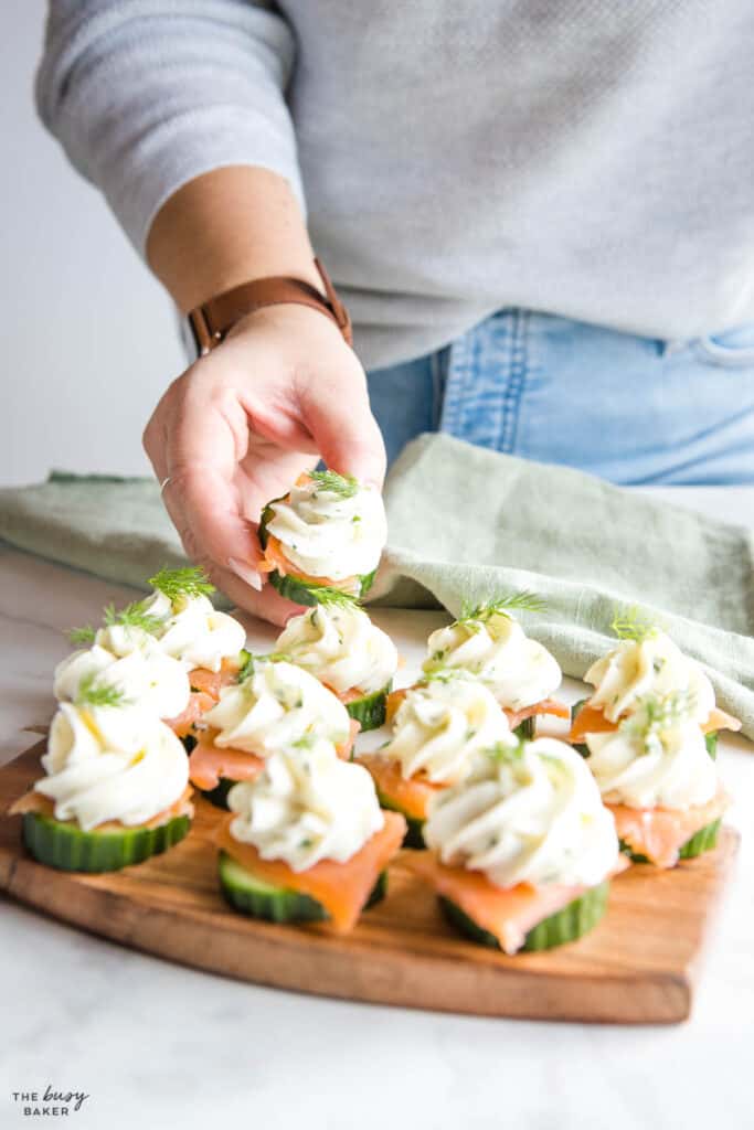 hand holding cucumber appetizer with dill and cream cheese