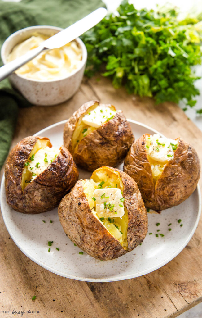 4 baked potatoes made in the air fryer with butter, chives, salt and pepper