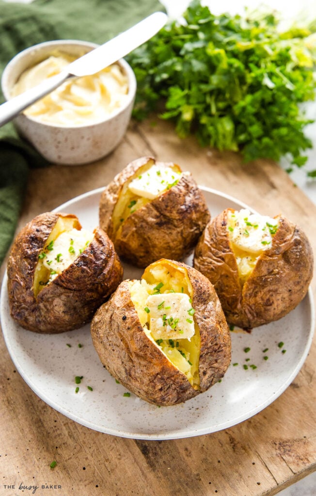 4 baked potatoes made in the air fryer with butter, chives, salt and pepper