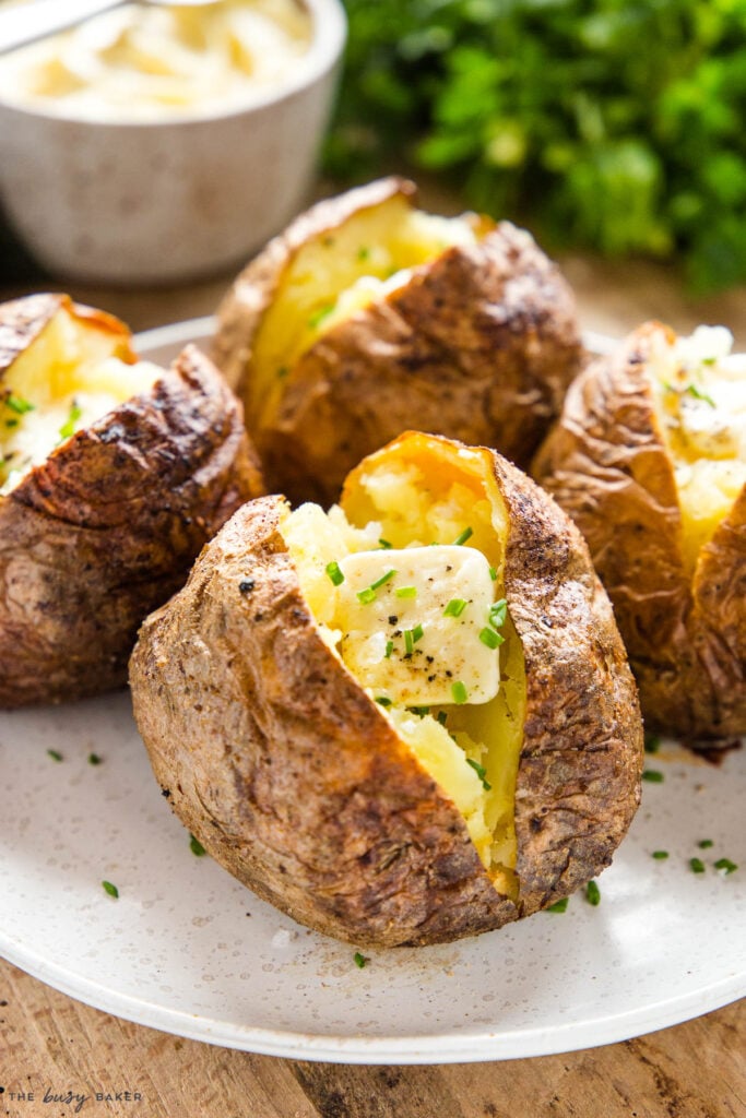 baked potato on plate with butter, chives, salt and pepper