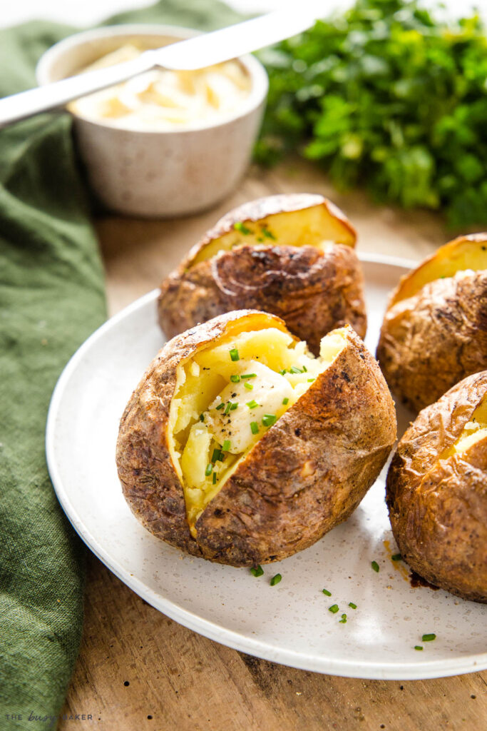 baked potato on plate with butter and chives