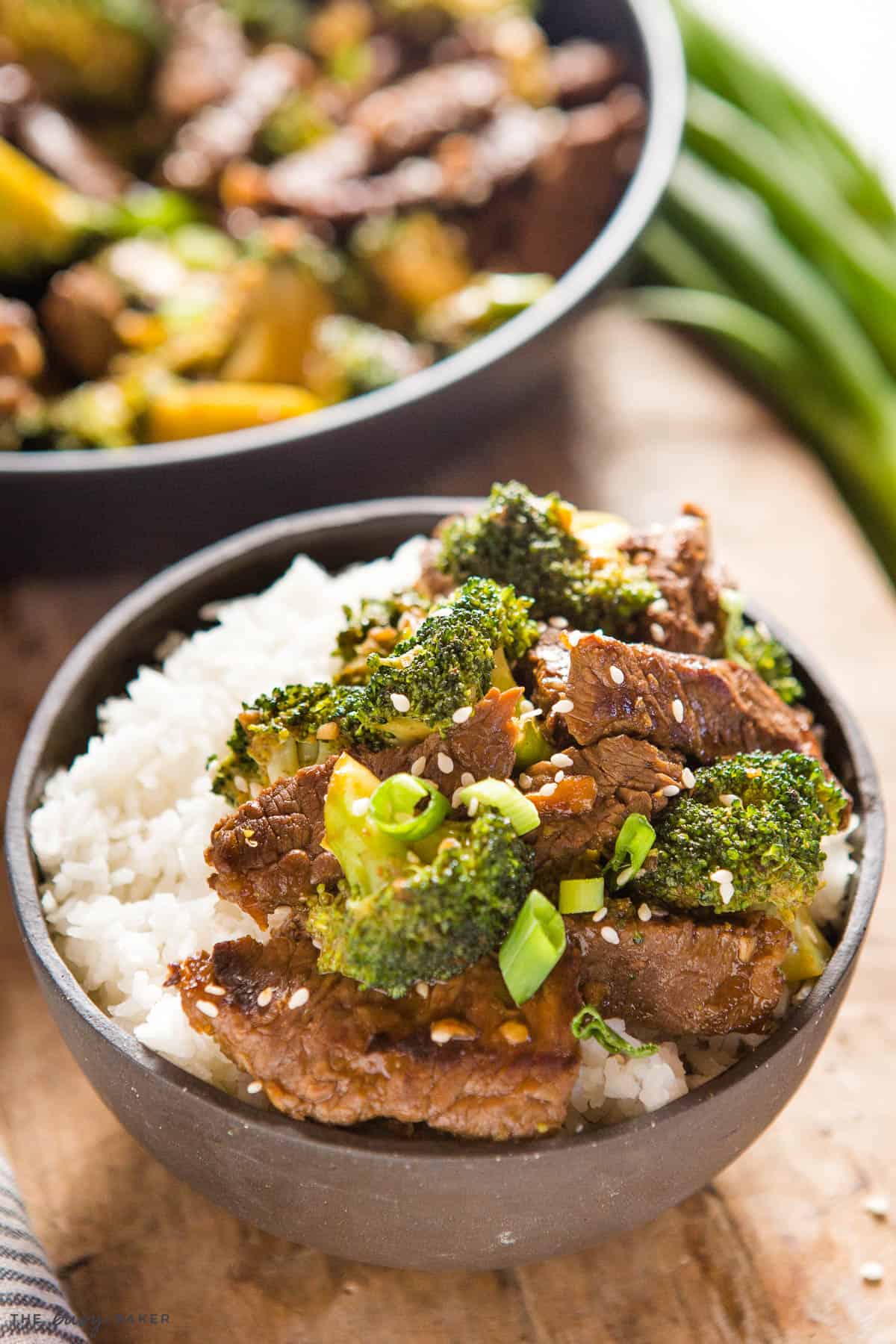 beef and broccoli stir fry over rice in a black bowl