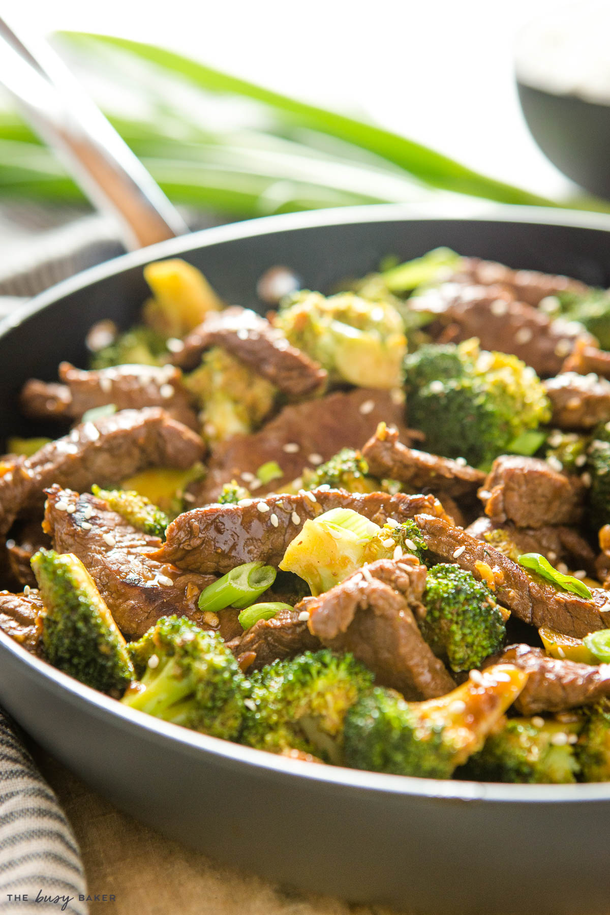 closeup image: beef and broccoli stir fry with sesame seeds and green onions