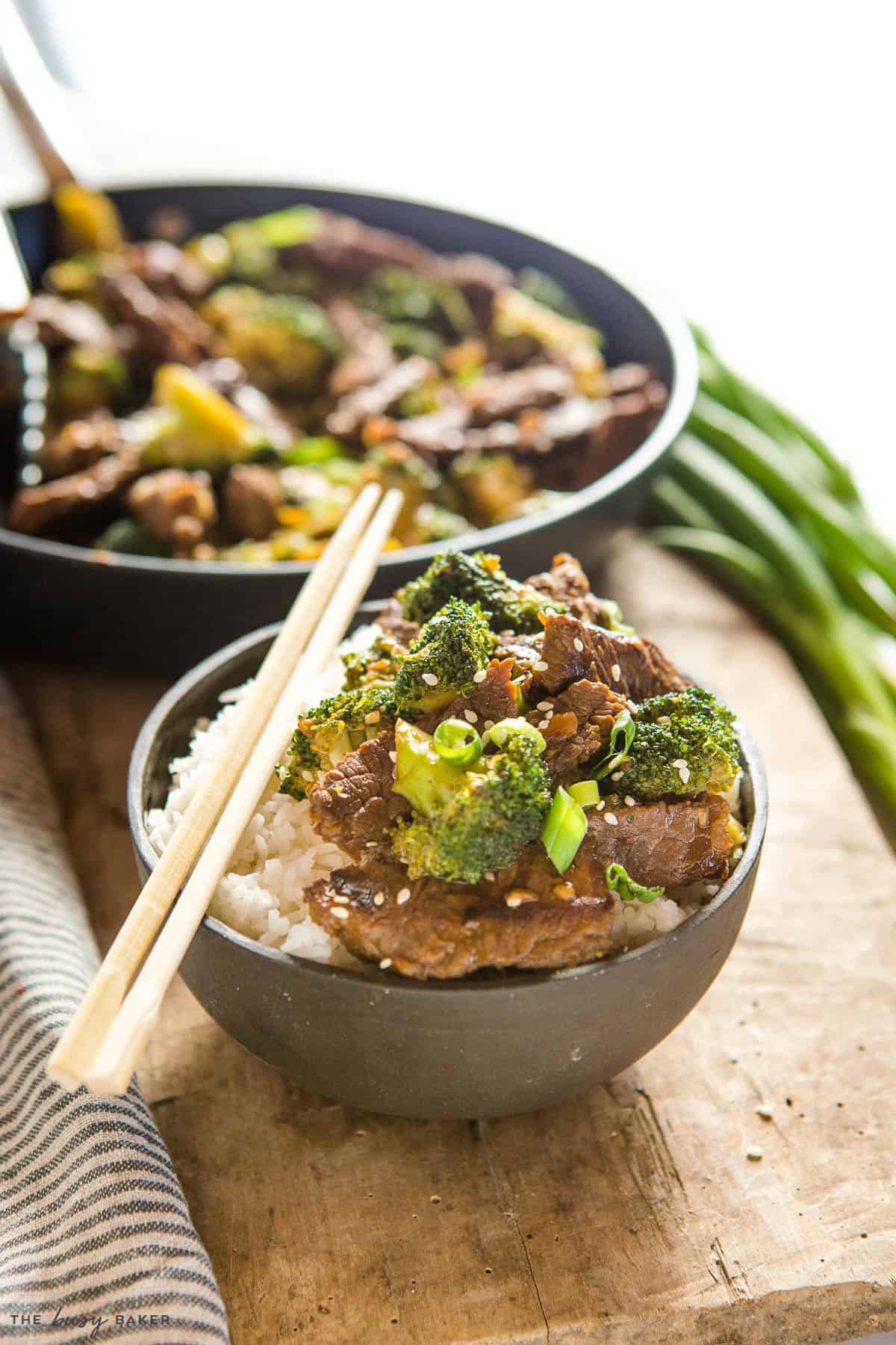 broccoli stir fry with beef over rice in a black bowl with chopsticks