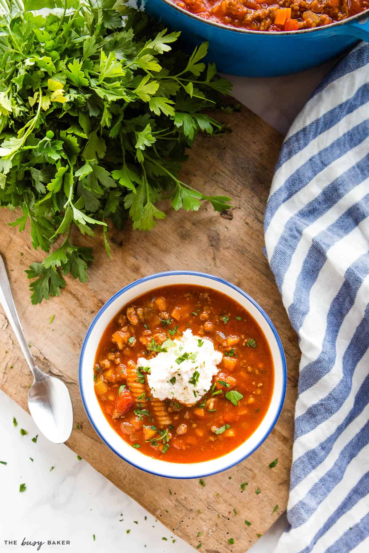 overhead image: lasagna soup with cheese on top in white bowl with blue rim