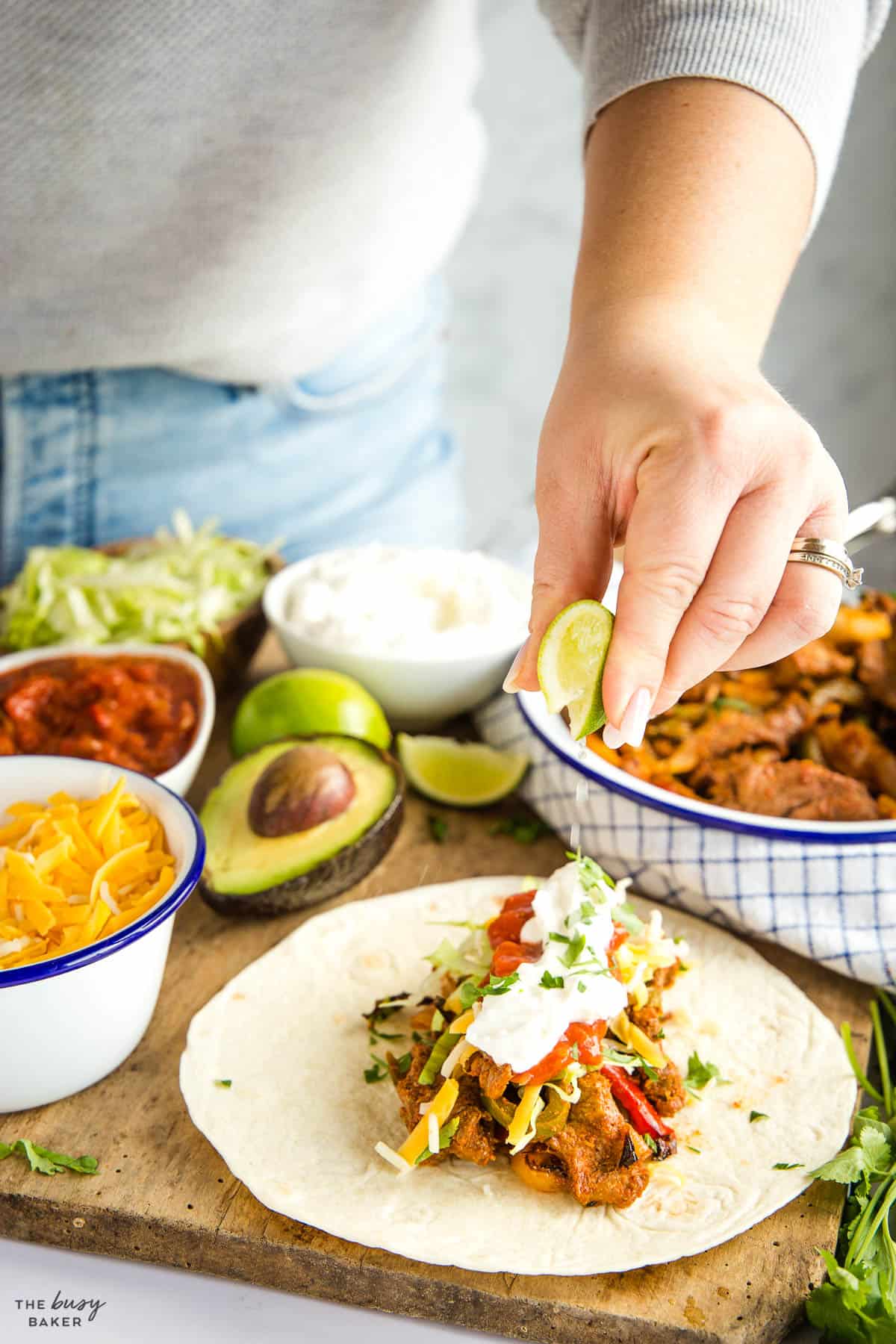 woman squeezing lime over a fajita with steak