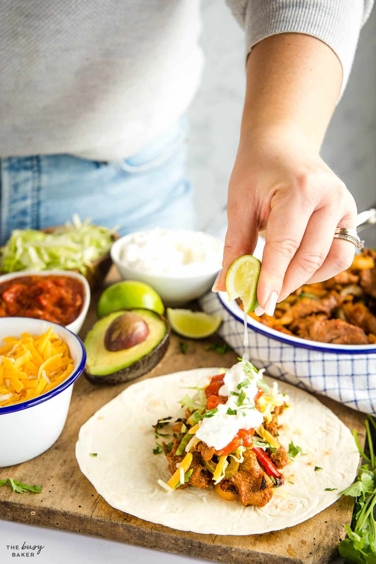 woman squeezing a lime over a fajita with steak 