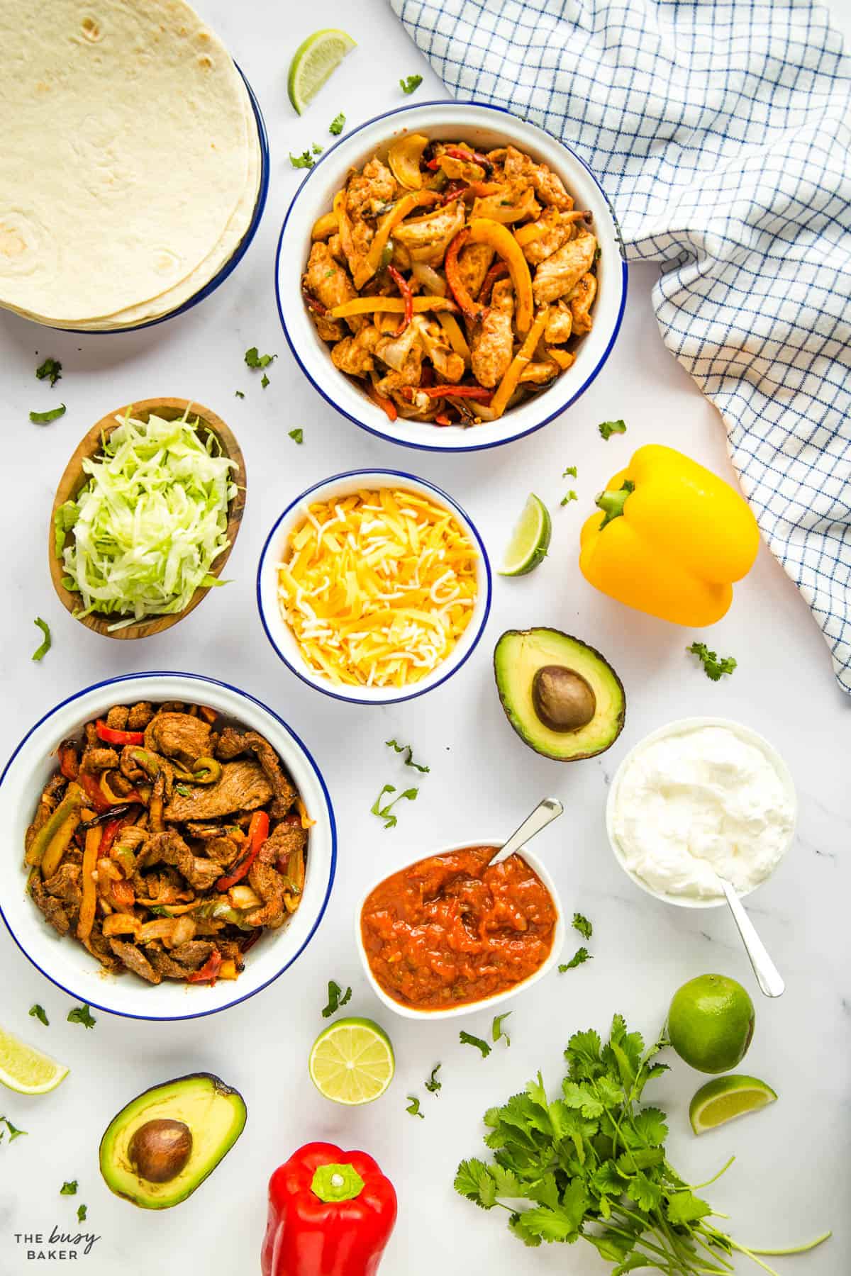 overhead image: chicken fajitas on platter with cheese, lime, sour cream, salsa and avocado