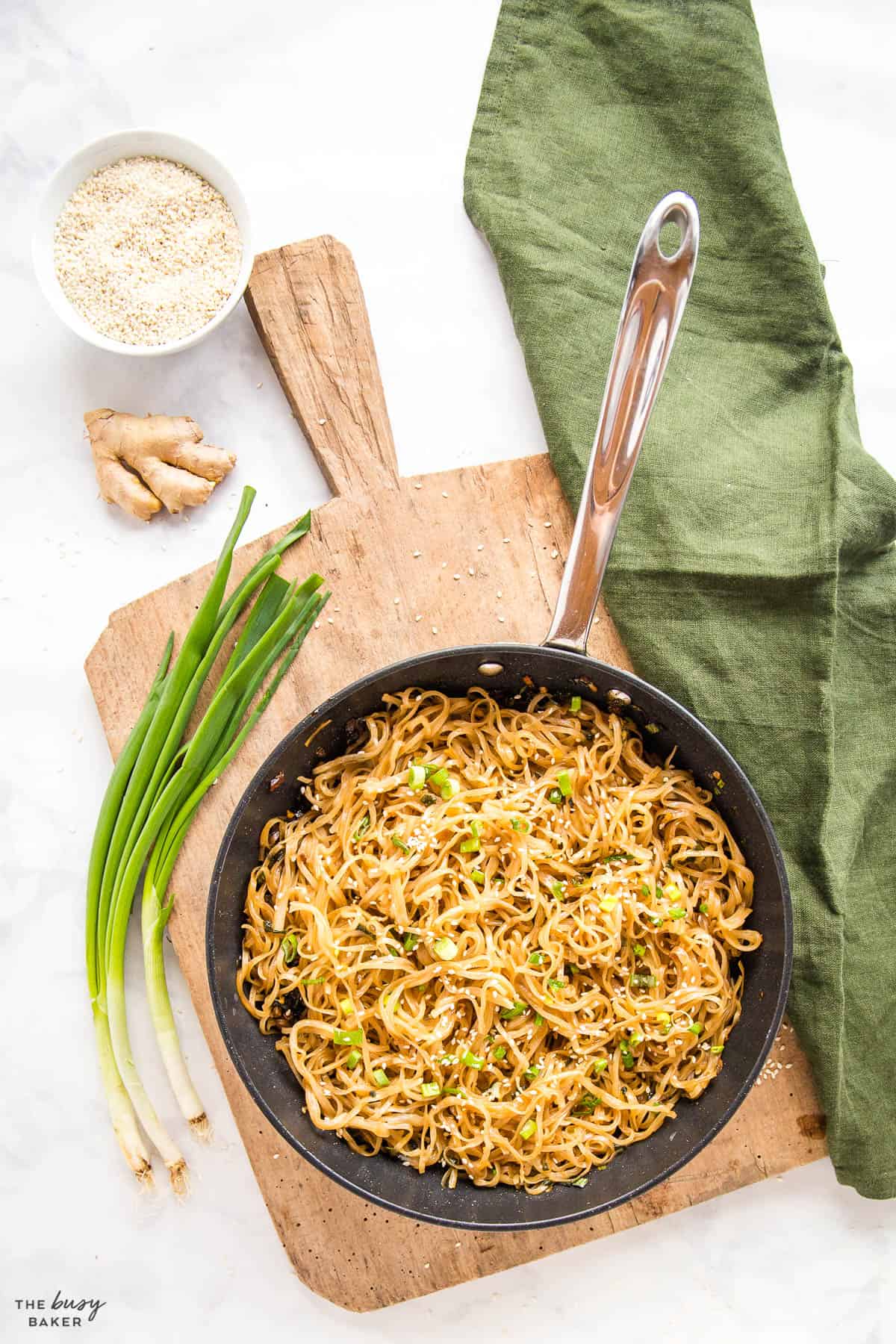 overhead image: frying pan with garlic noodles, green onions and sesame seeds
