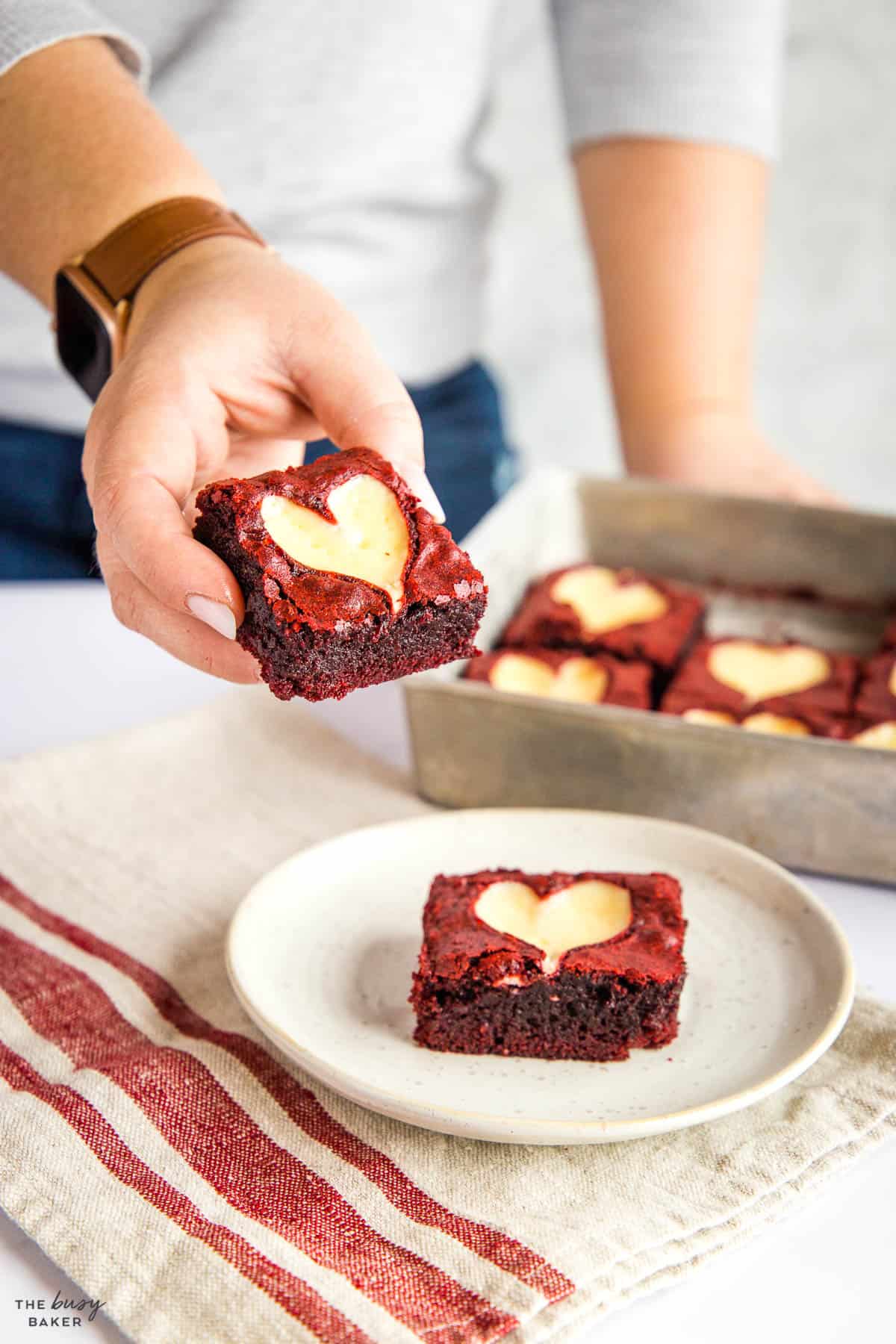 hand holding red velvet brownie with cream cheese heart design