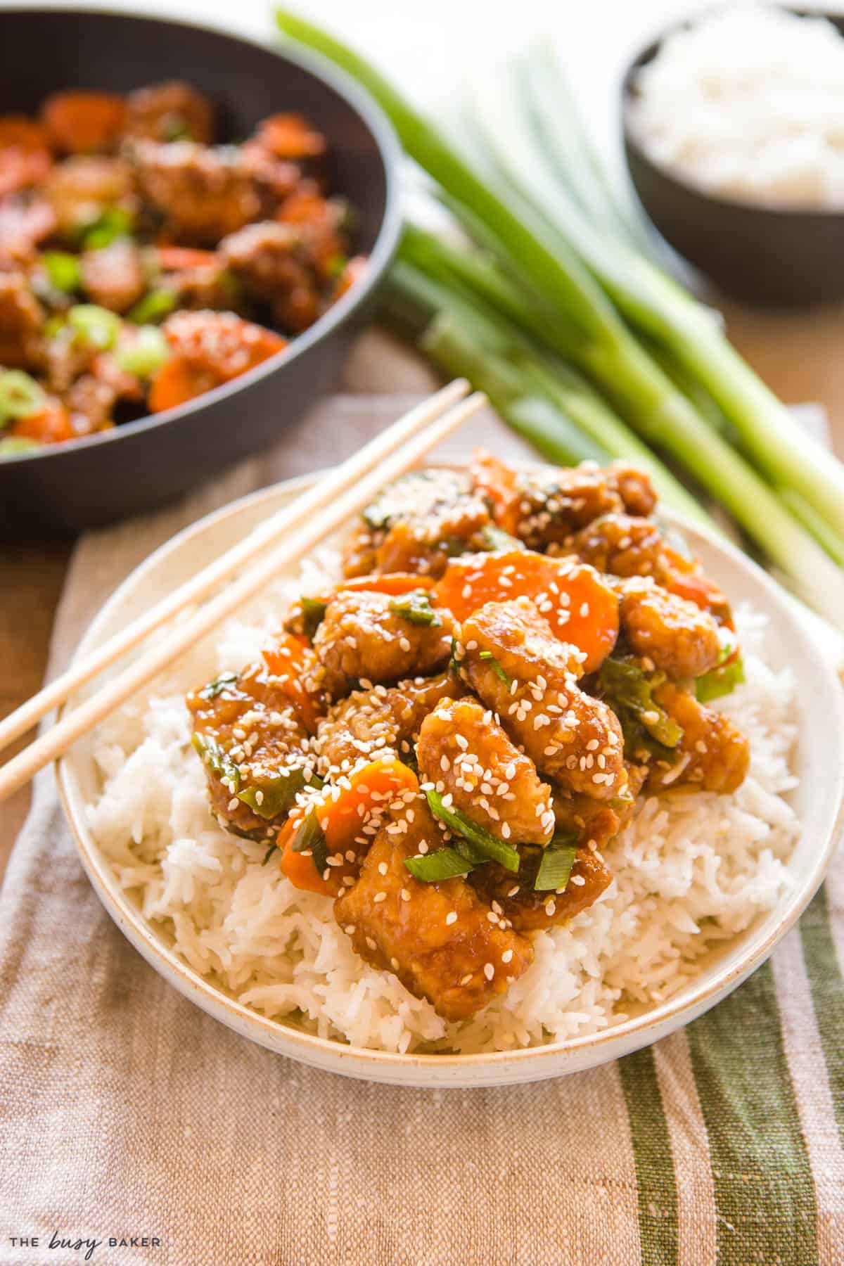 bowl of rice with sesame chicken with carrots and sesame seeds