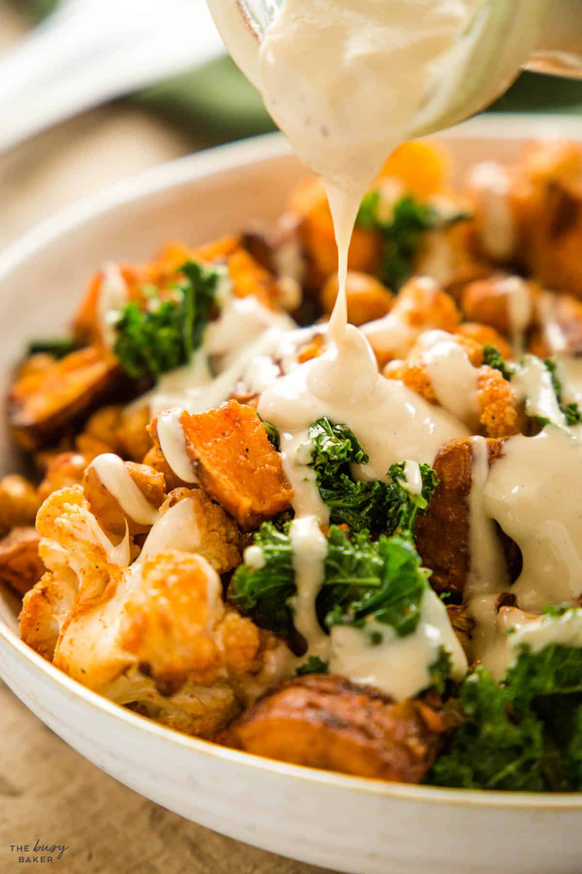 tahini dressing pouring over a sweet potato and kale power bowl