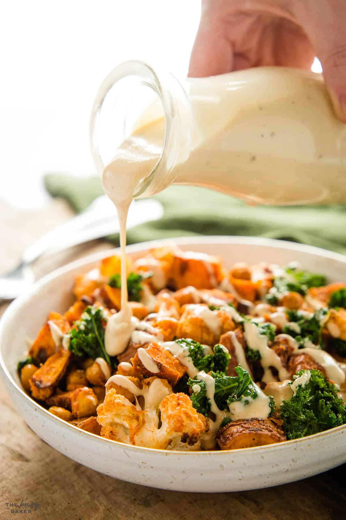 white creamy sauce being poured over a vegan power bowl