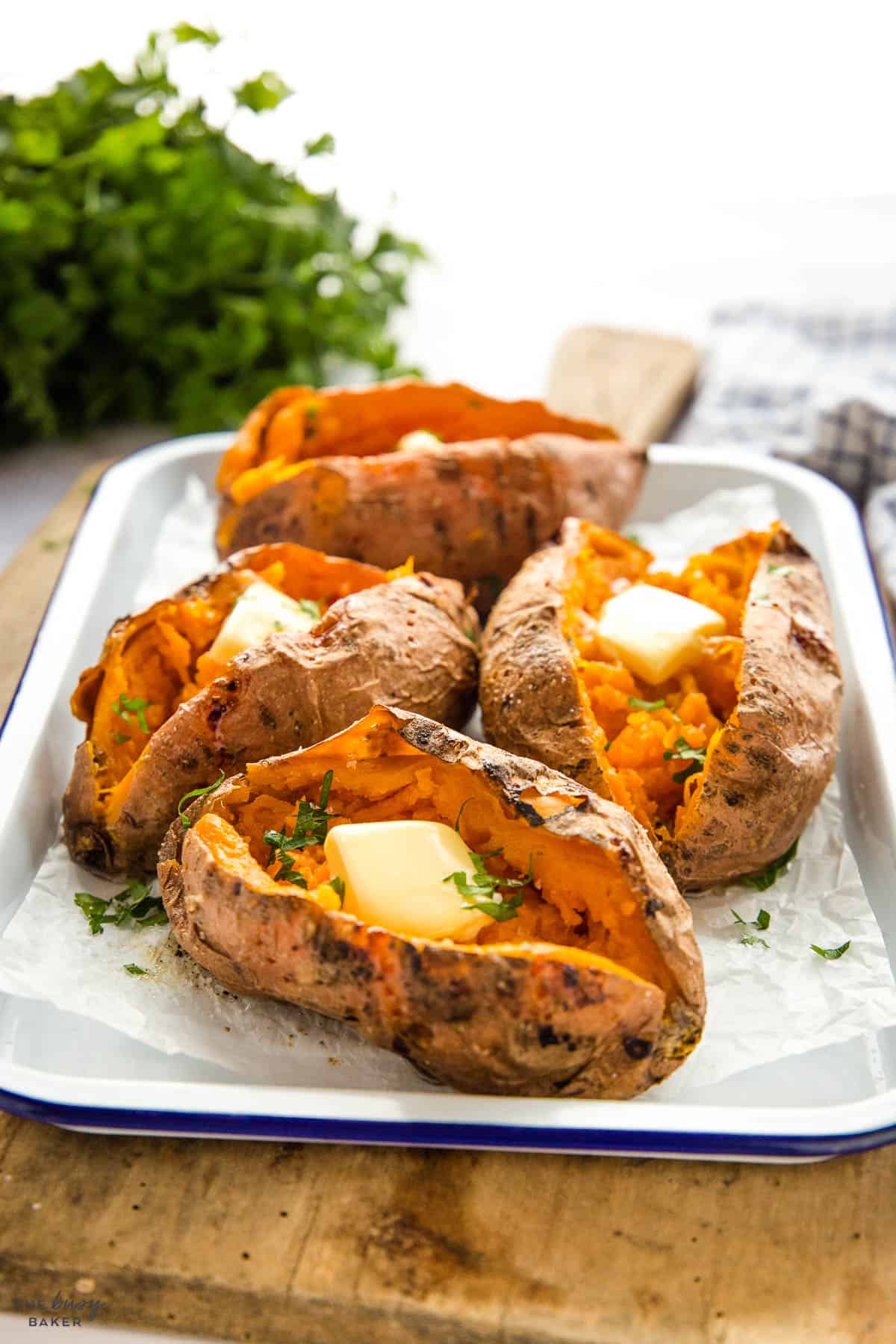 air fryer baked sweet potatoes on white tray with butter