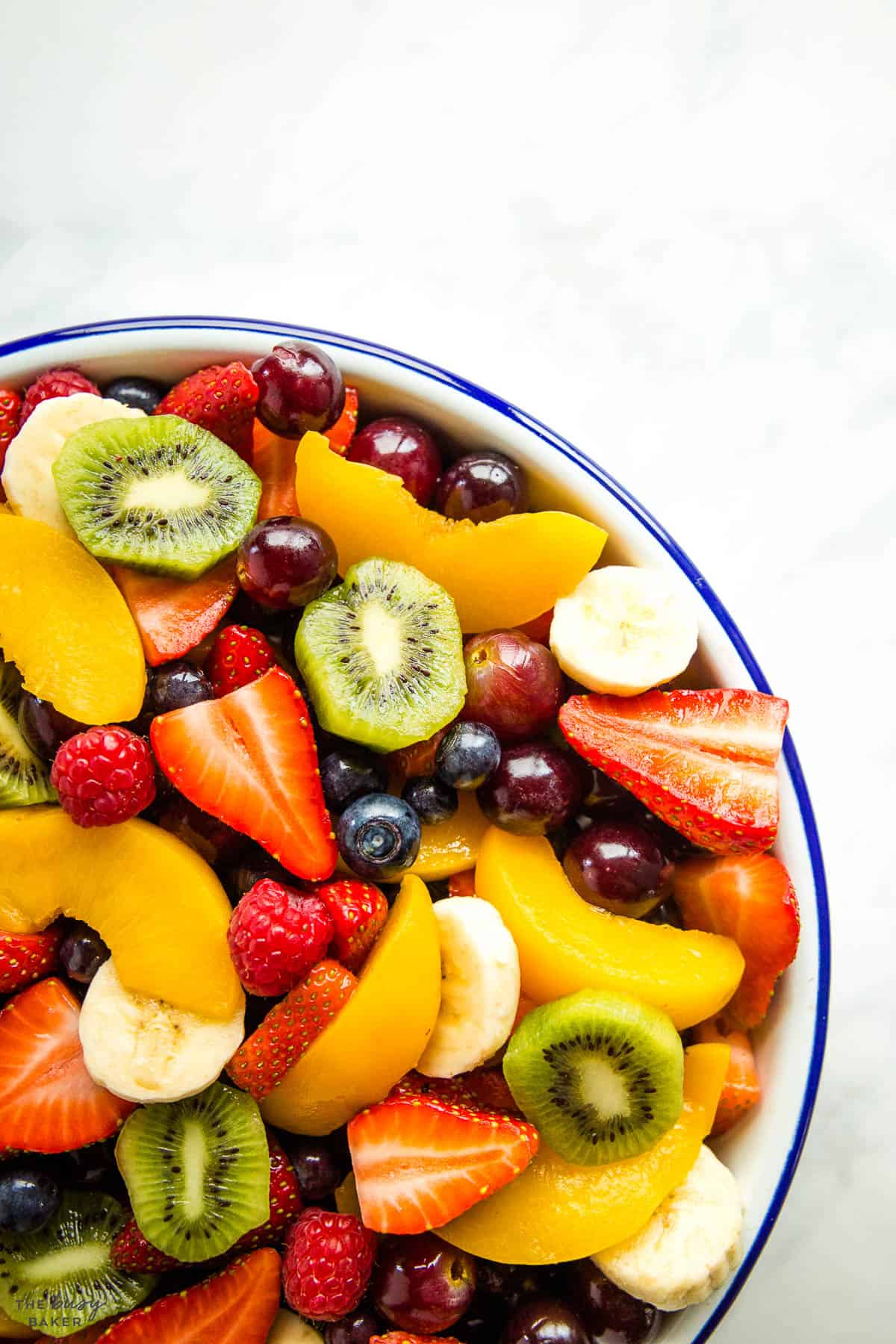 overhead image: mixed fruit in a white bowl with a blue rim