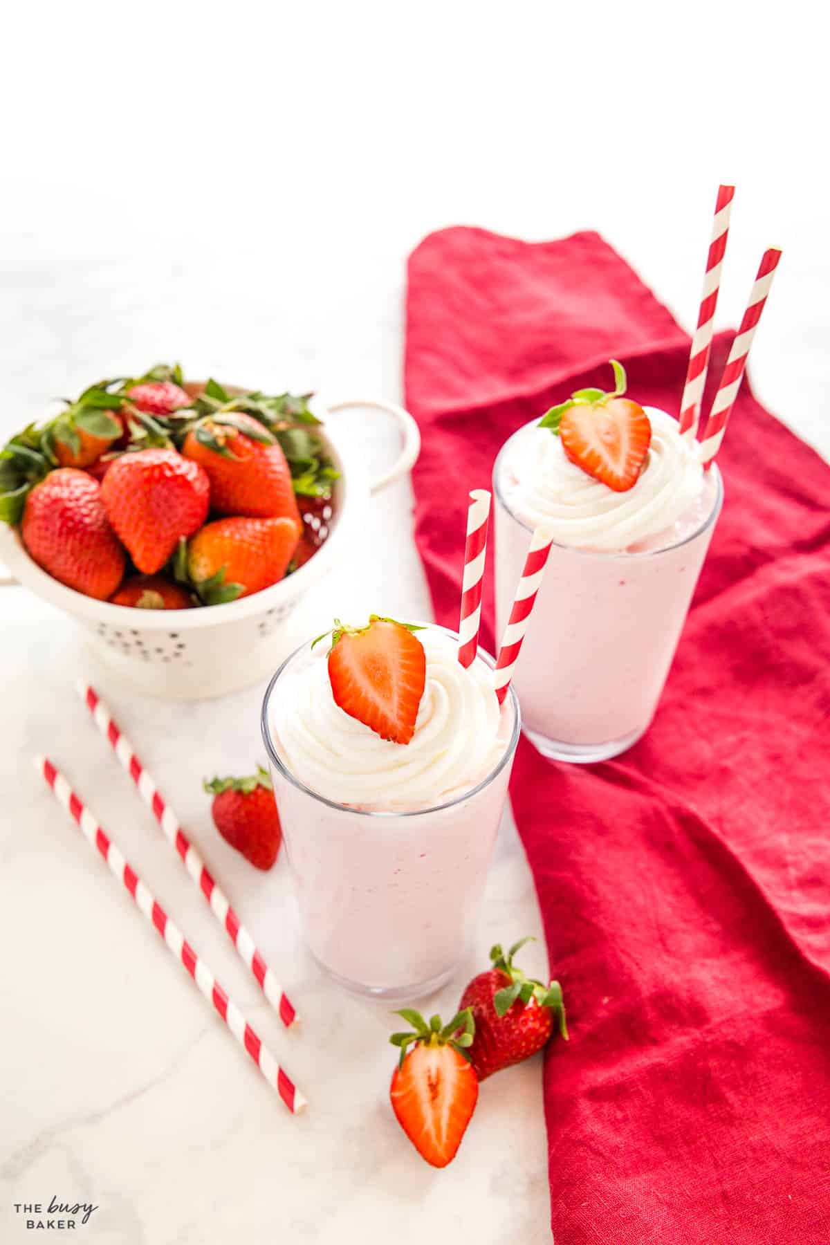 strawberry milkshakes with red paper straws and fresh strawberries