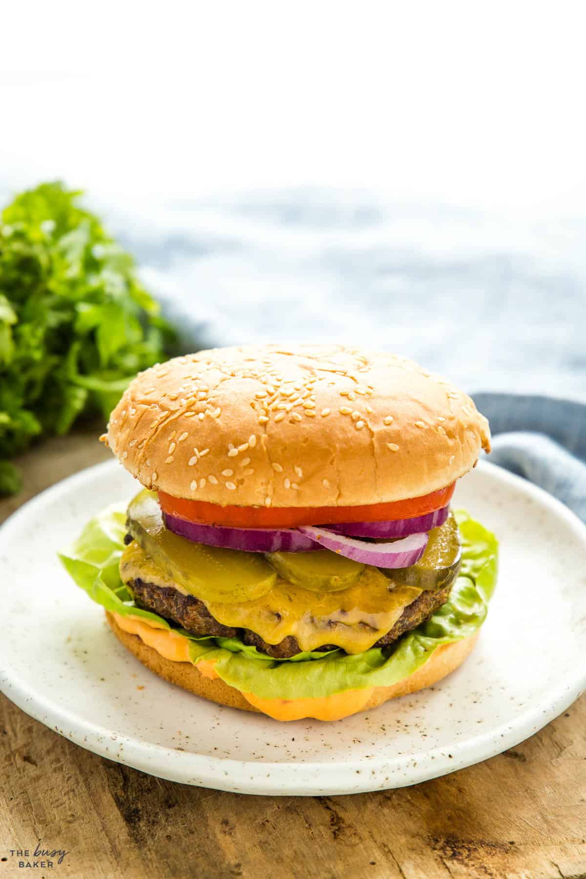 cheeseburger on a sesame seed bun with pickles, onions, tomato, lettuce and burger sauce