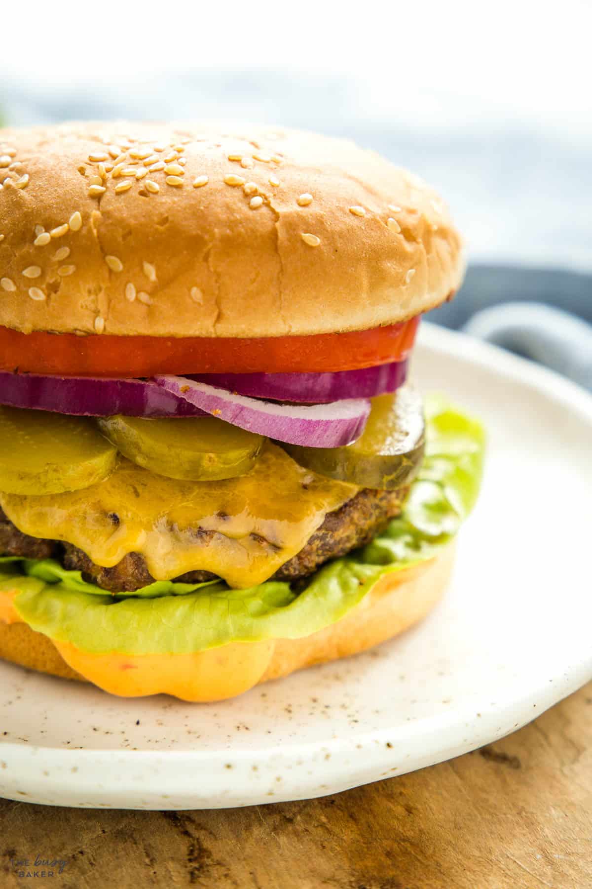 close up image: cheeseburger with pickles, onions, lettuce, tomato and burger sauce
