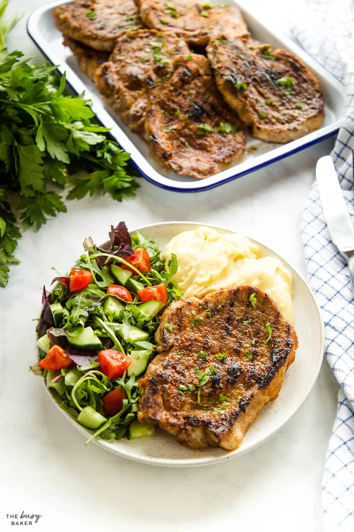pork steak on white plate with salad and mashed potatoes