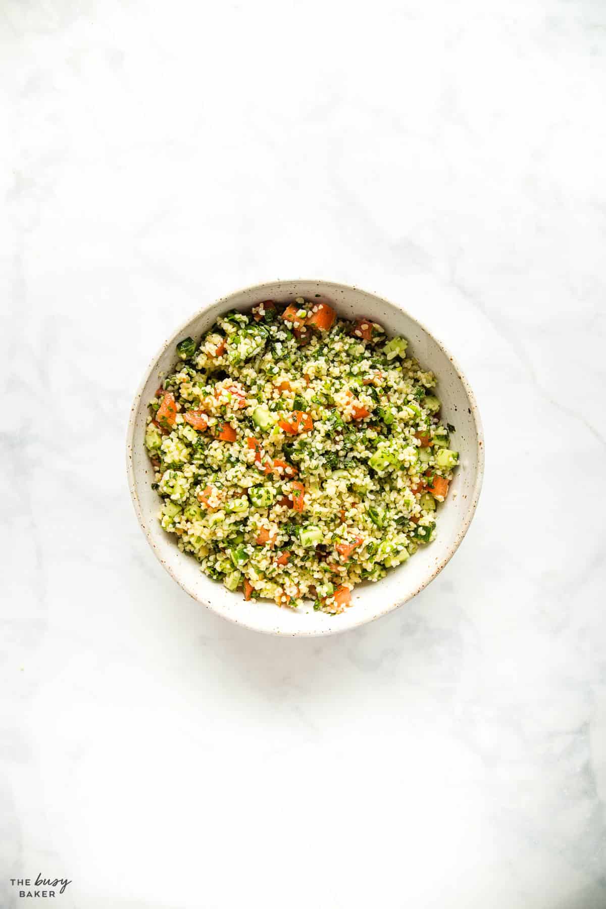salad in a ceramic bowl with bulgur, veggies, and fresh herbs
