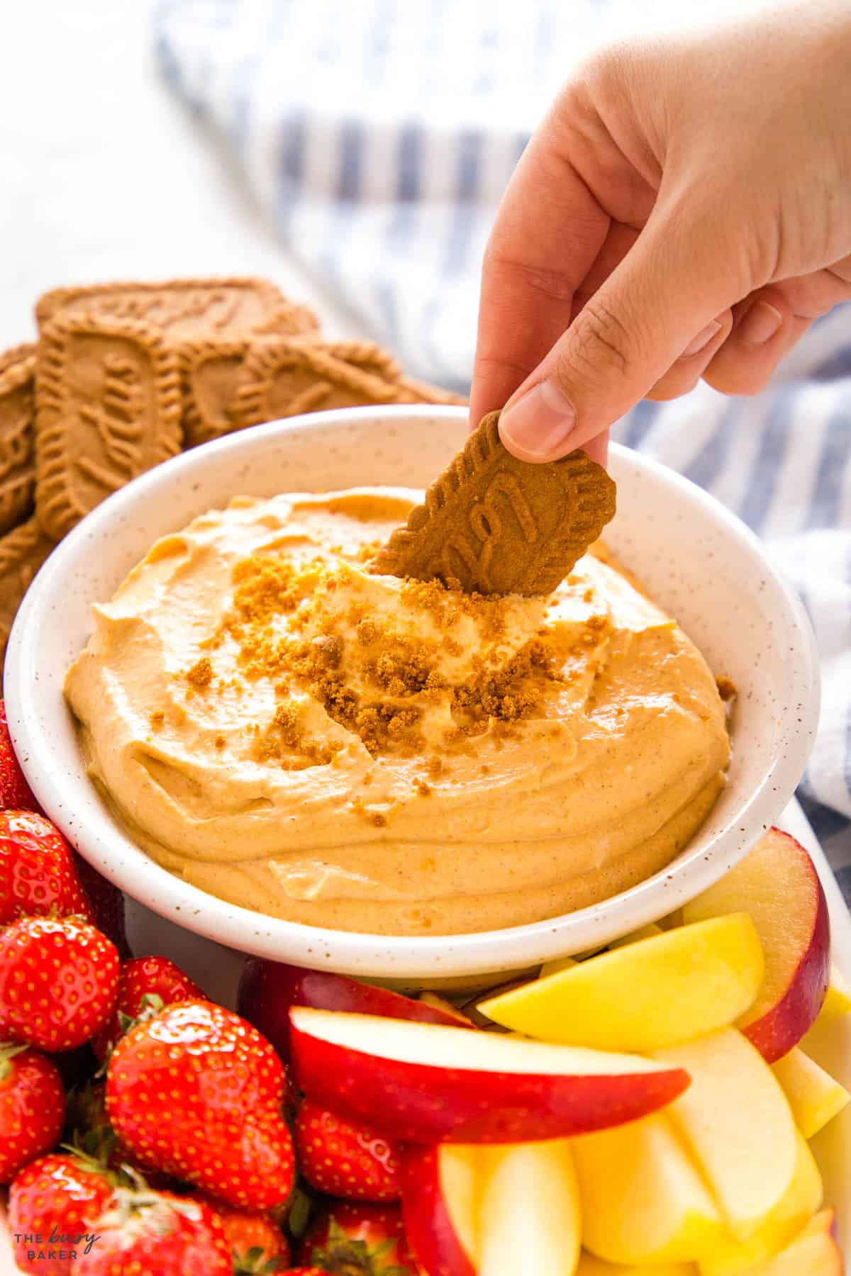 hand dipping cookie into fluffy dessert cream