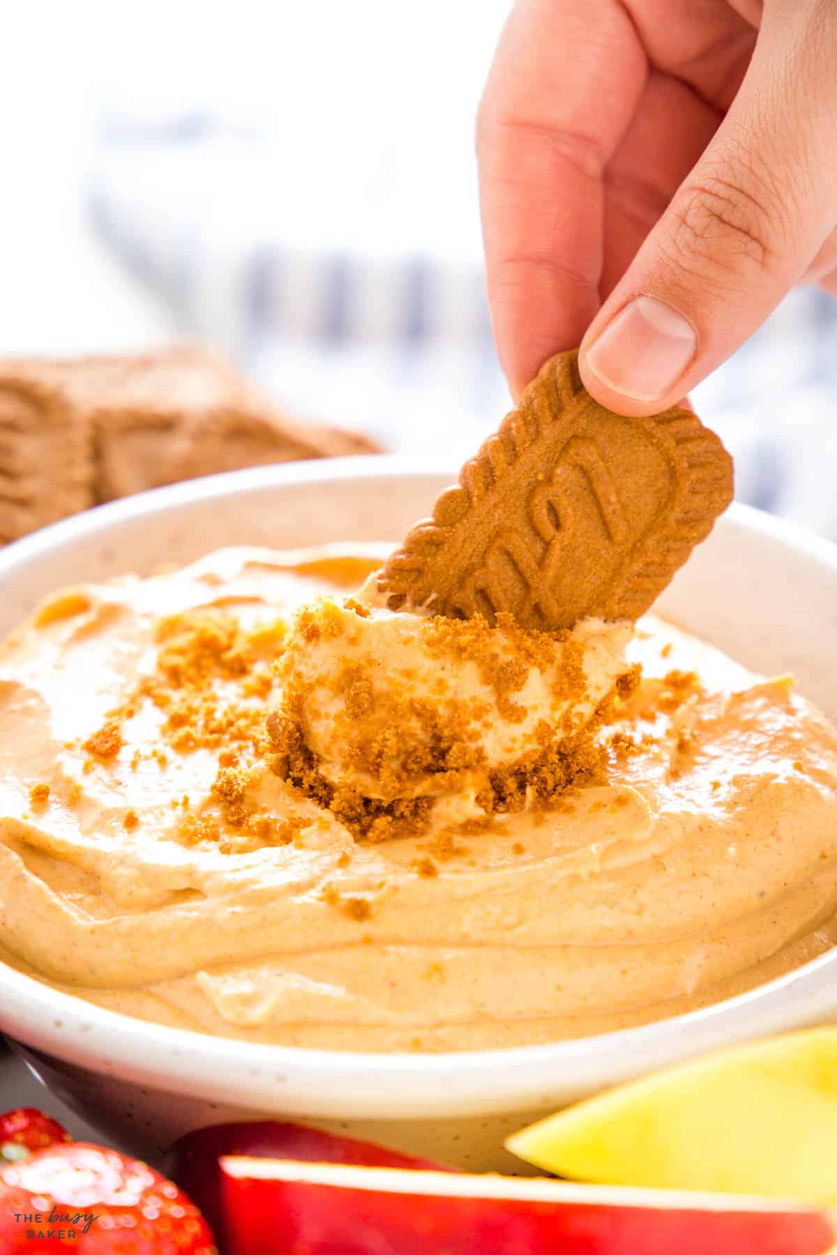 hand dipping a cookie into pumpkin dip