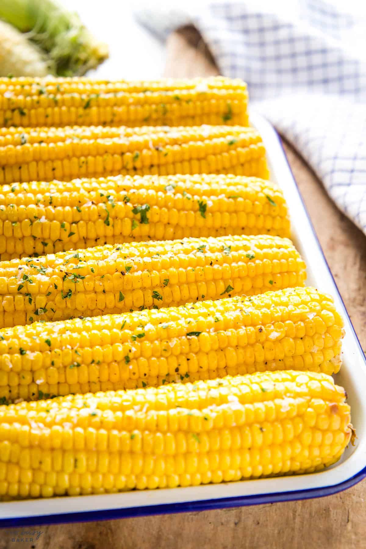 platter of corn cobs with fresh herbs and salt