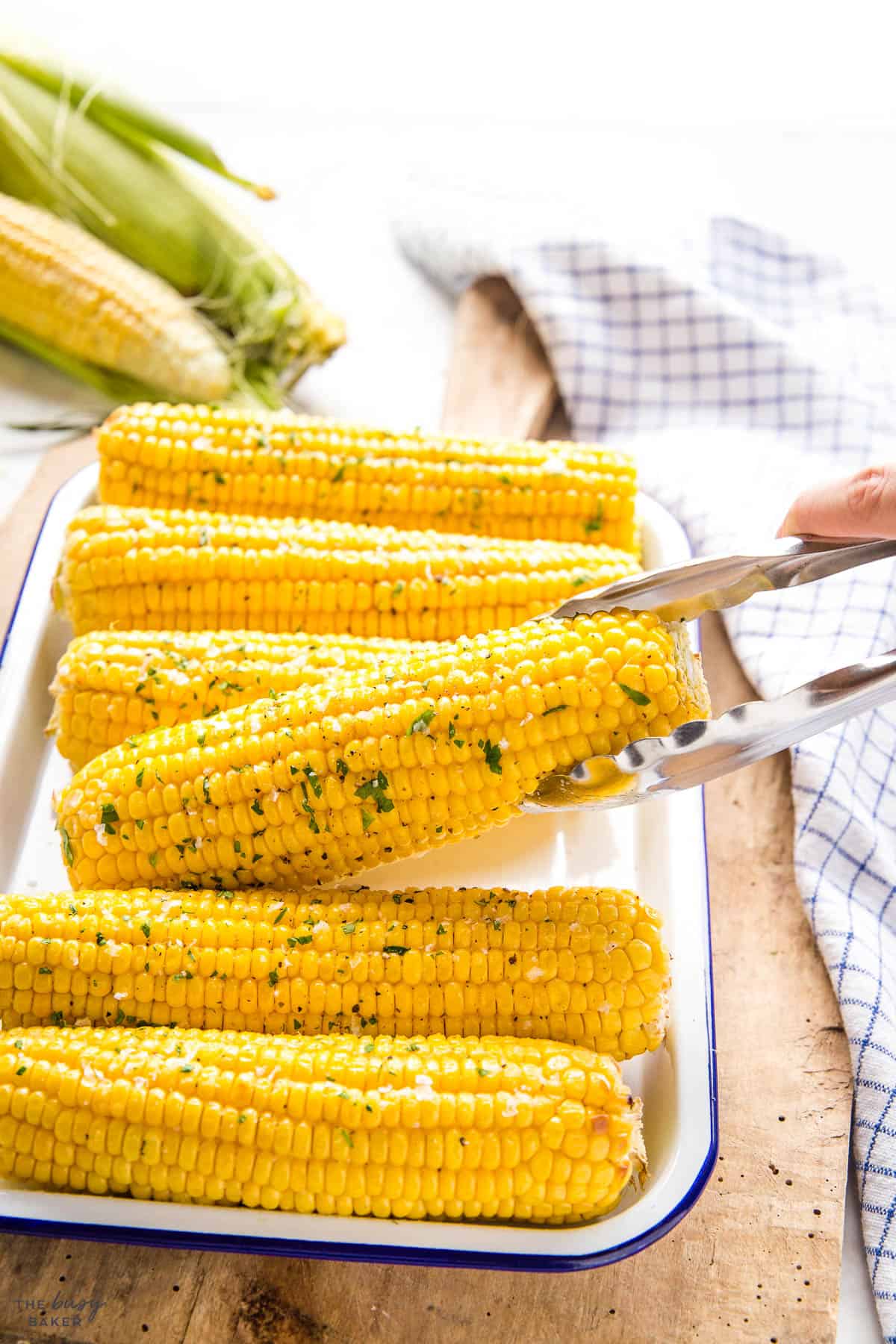 hand holding tongs serving corn on the cob