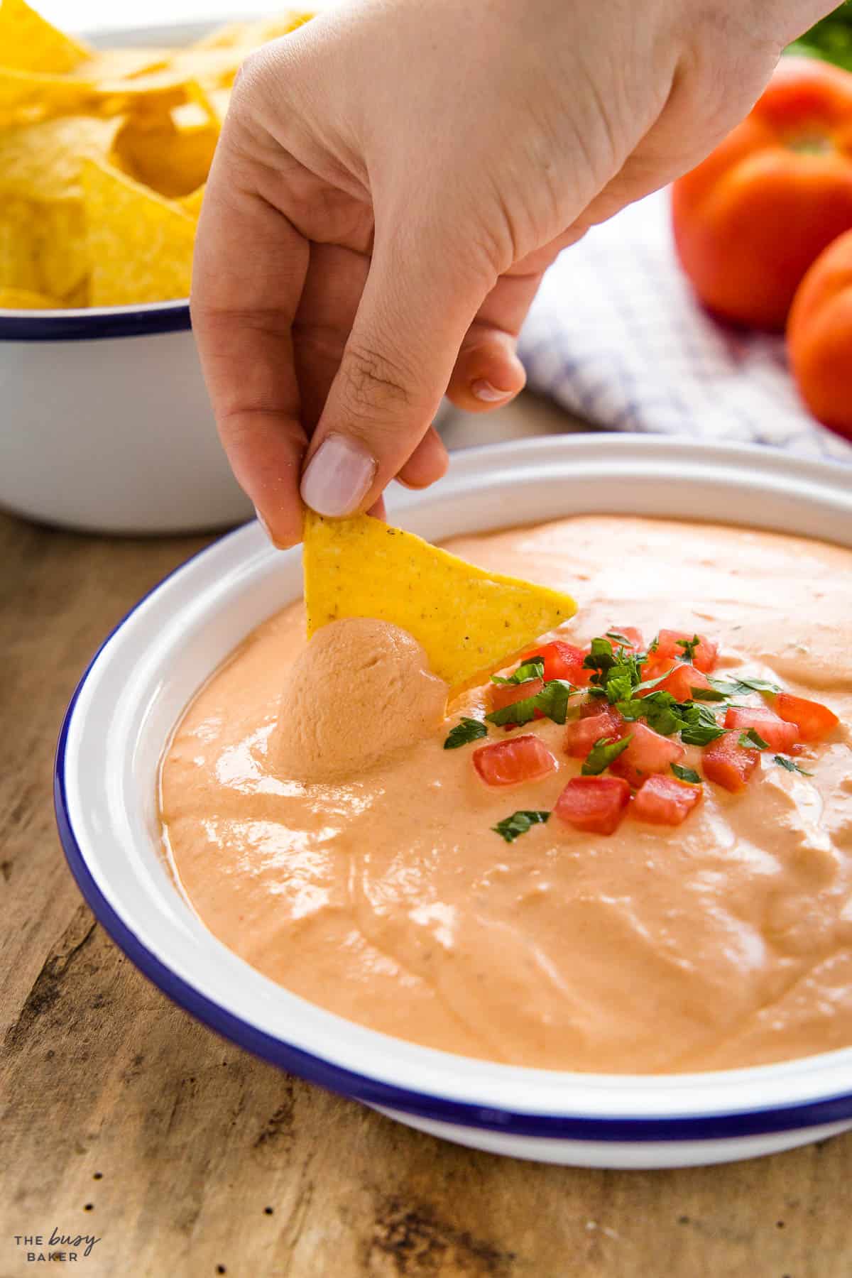 hand dipping tortilla chip in creamy queso dip made with cottage cheese