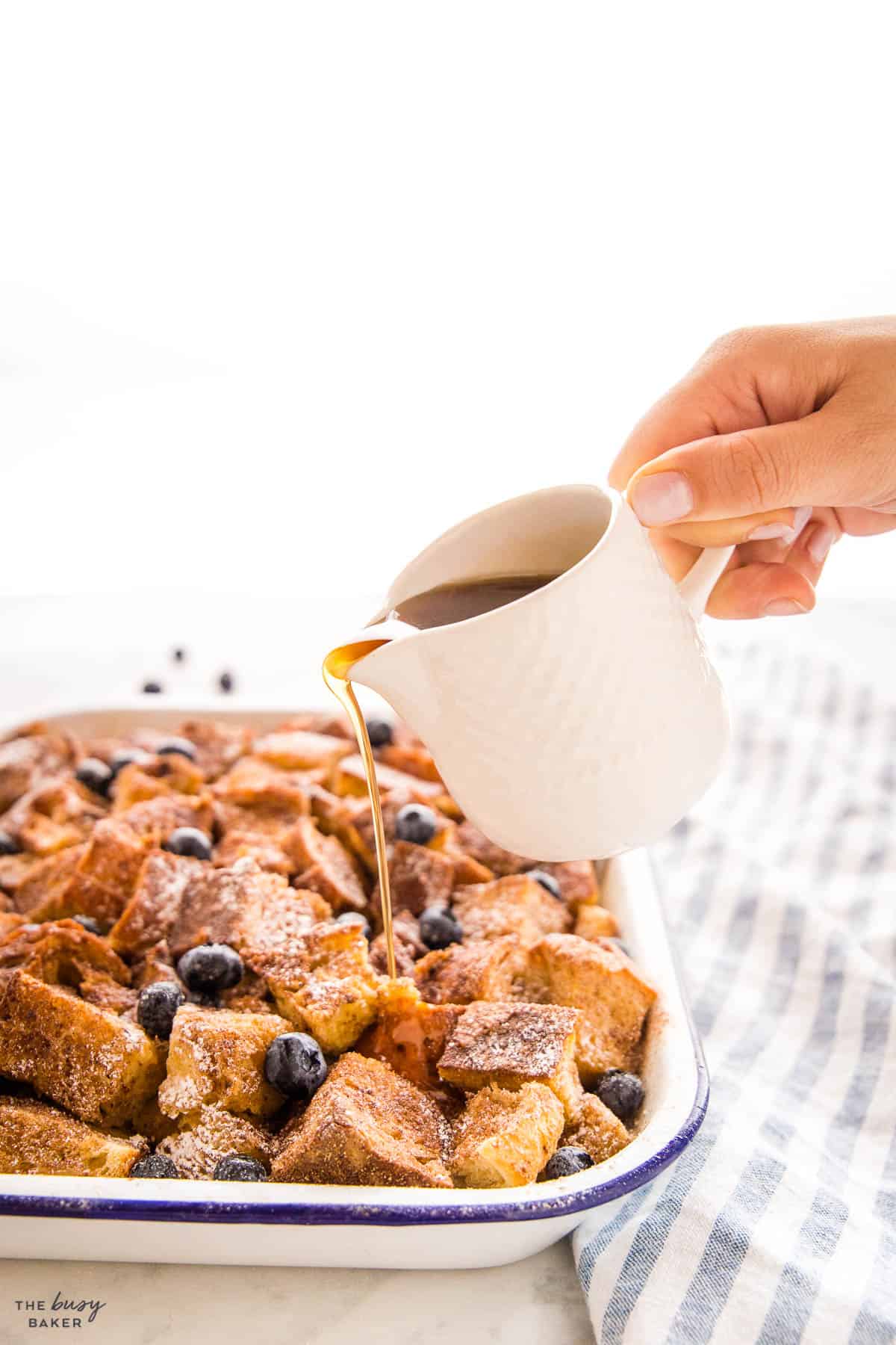 hand pouring syrup on overnight french toast casserole recipe