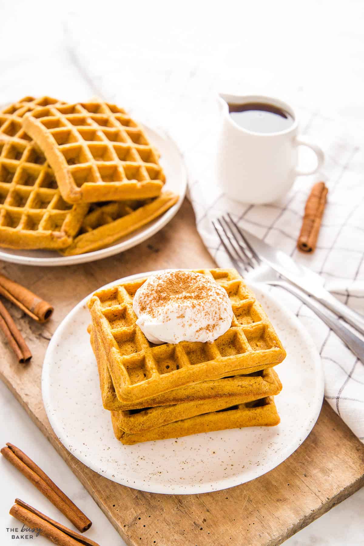stack of waffles made with pumpkin and served with whipped cream and cinnamon