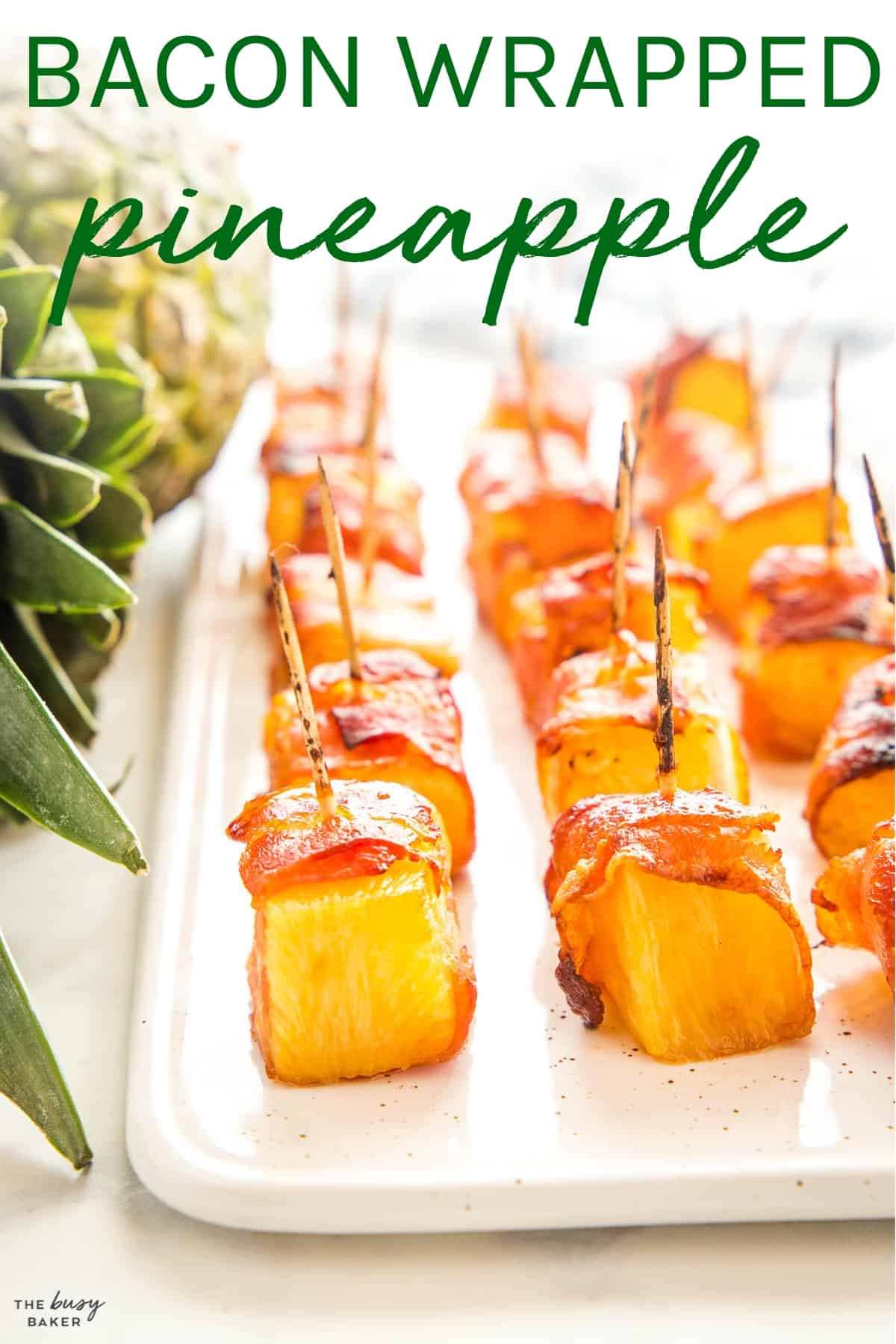 bacon wrapped pineapple on a platter with toothpicks