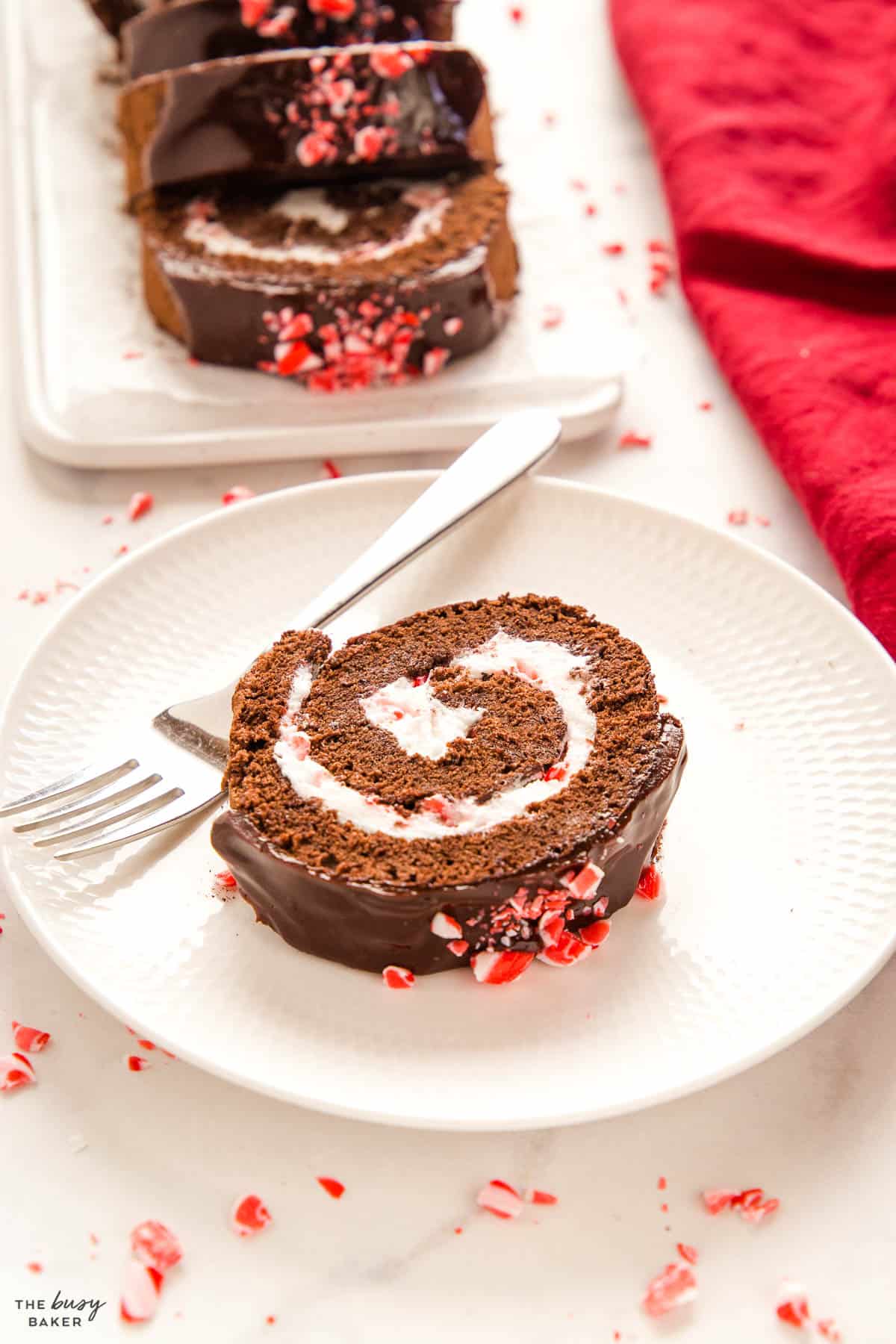 slice of peppermint chocolate Swiss roll cake with crushed candy canes