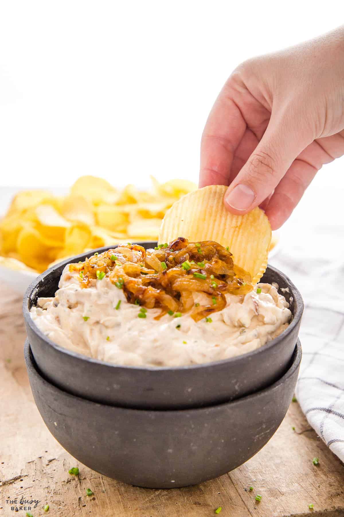 hand dipping a chip into chip dip
