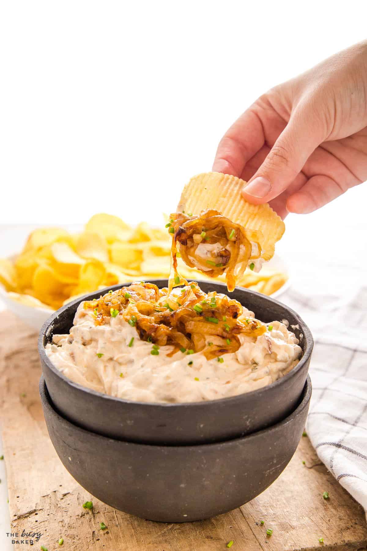 hand dipping a chip info French Onion Dip