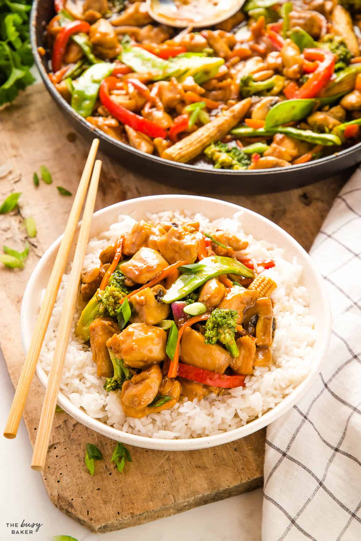 bowl of rice with chicken vegetable stir fry on top with sauce and chopsticks