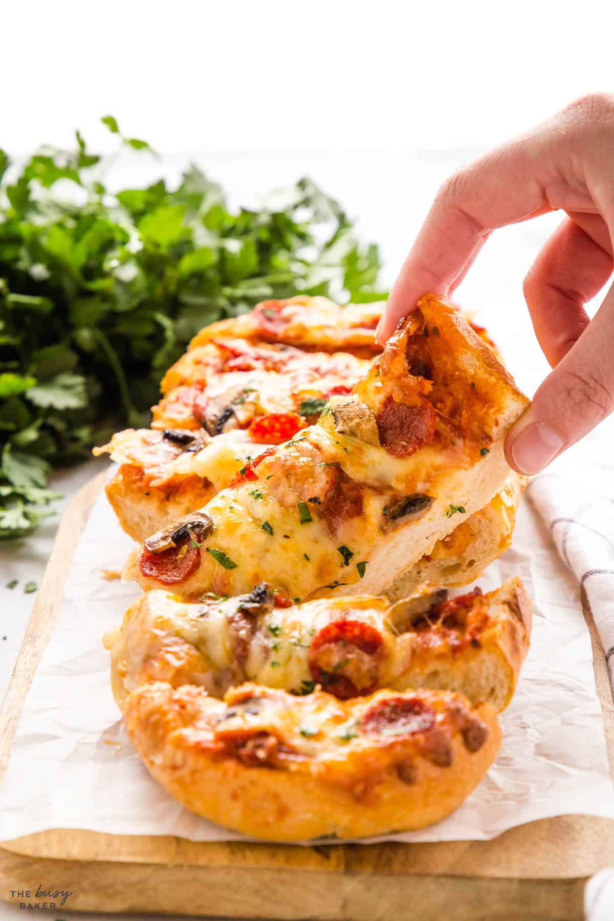 hand holding a slice of french bread pizza