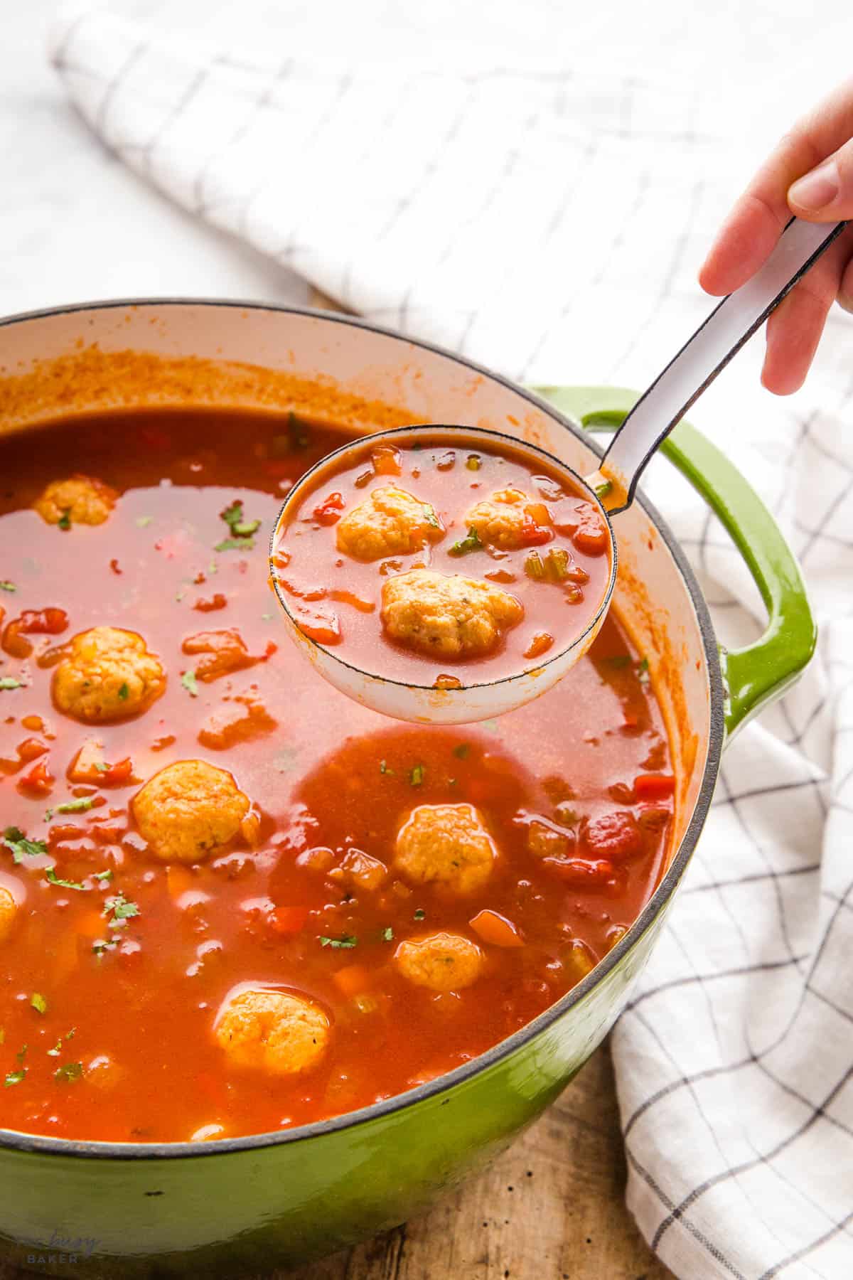 hand serving meatball soup in a soup ladle
