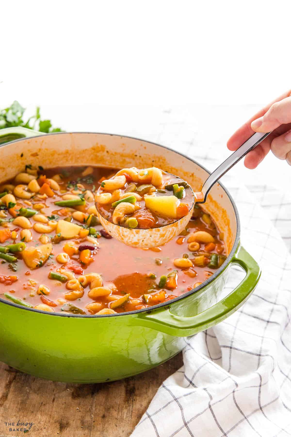 hand serving a ladle of Italian vegetable soup