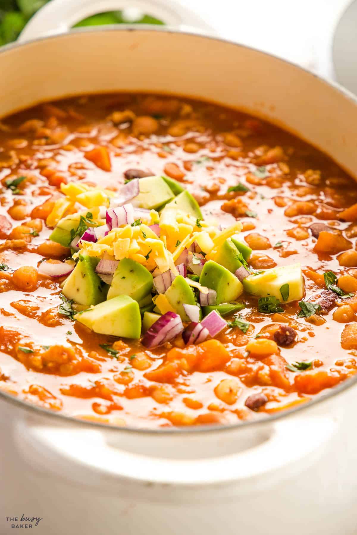 avocado, cheese and onion on top of ground turkey chili in a pot