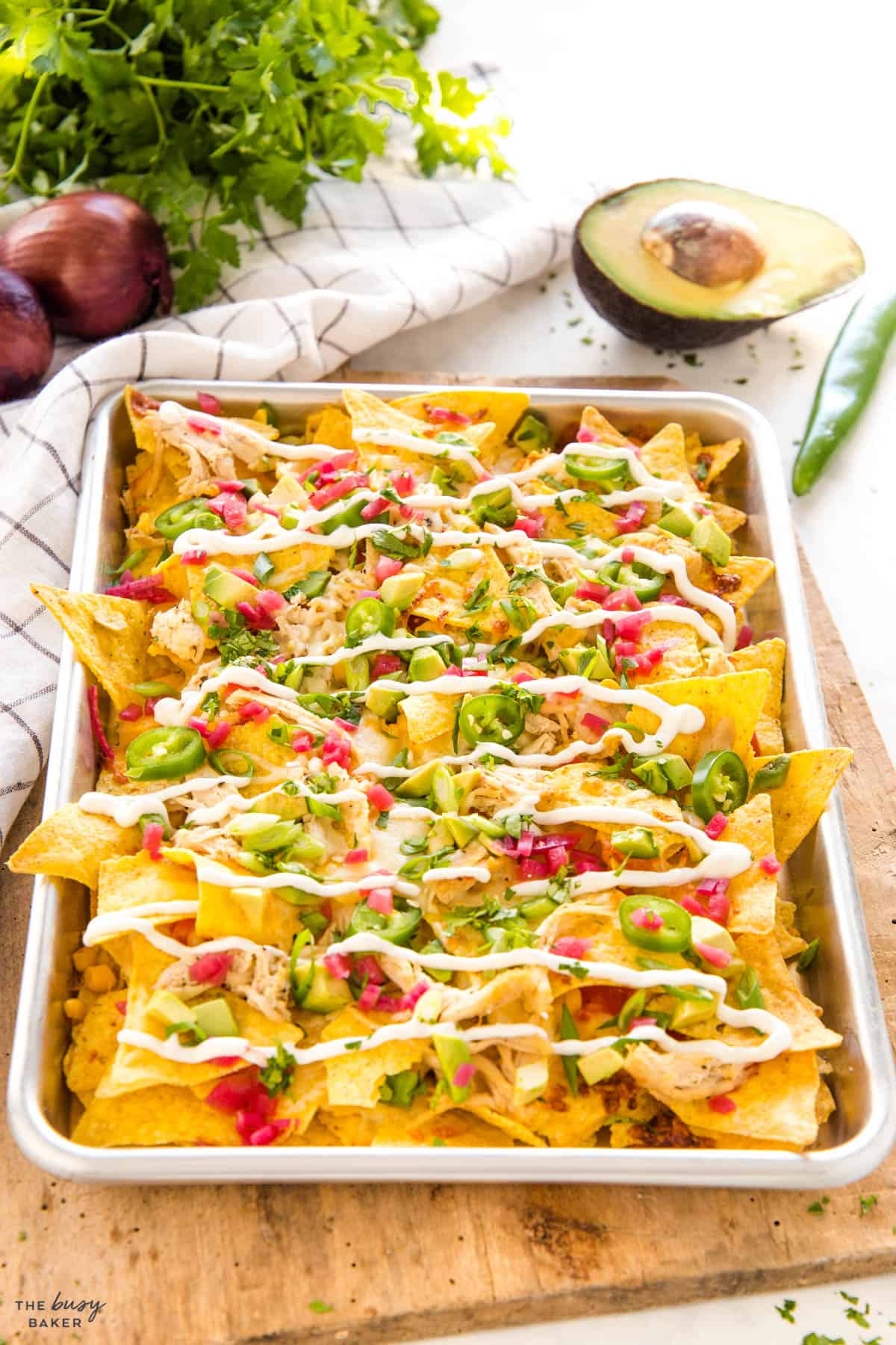 sheet pan loaded with tortilla chips, red peppers, green onion, jalapeno and cheese