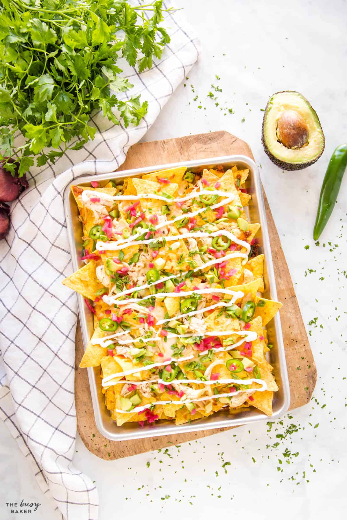 overhead image: a rectangle sheet pan full of tortilla chips with red peppers, onions, jalapeno