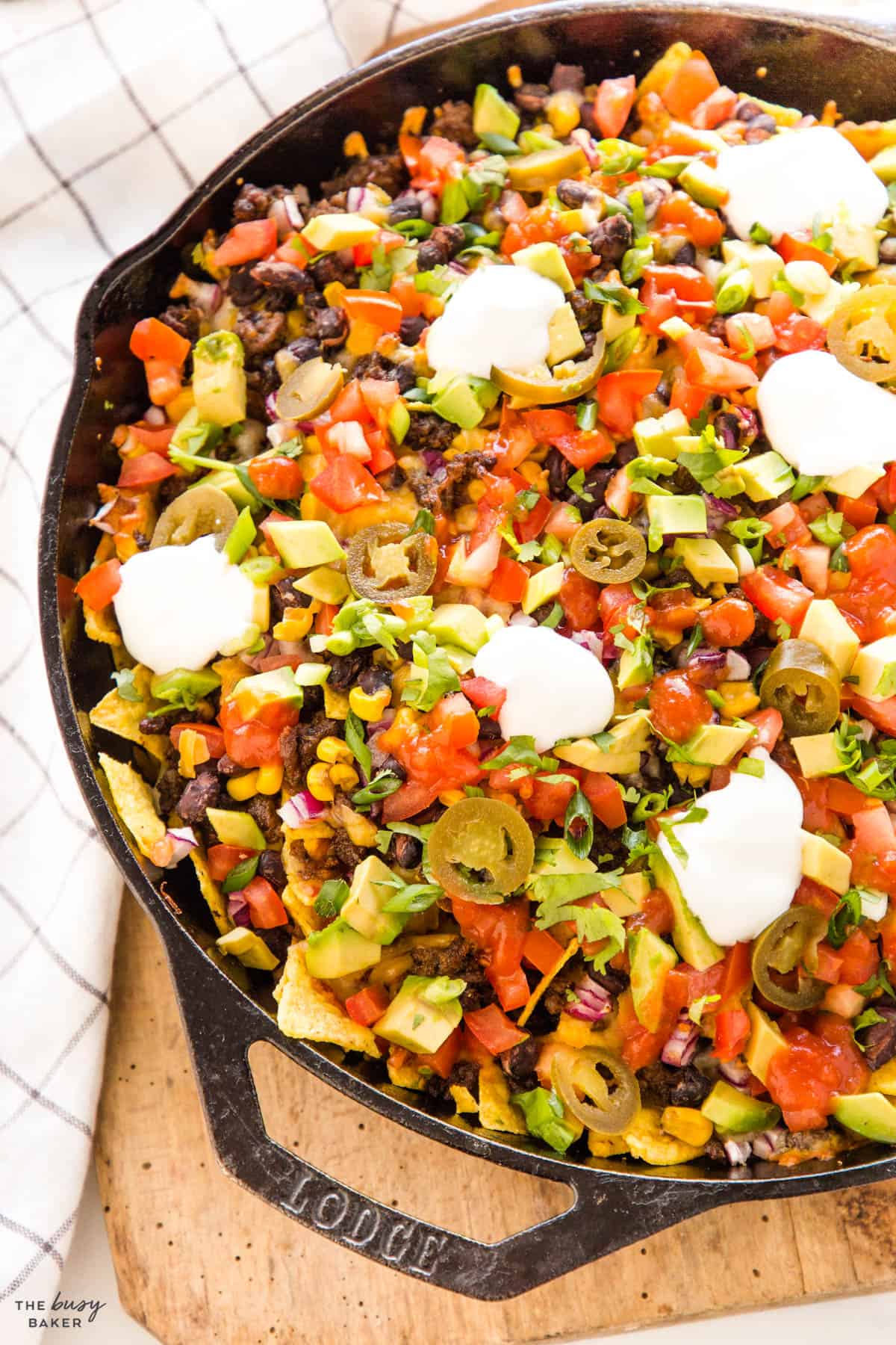 close up image: tortilla chips, corn, beans, tomatoes, avocado, red onion, jalapeno and sour cream dallops 