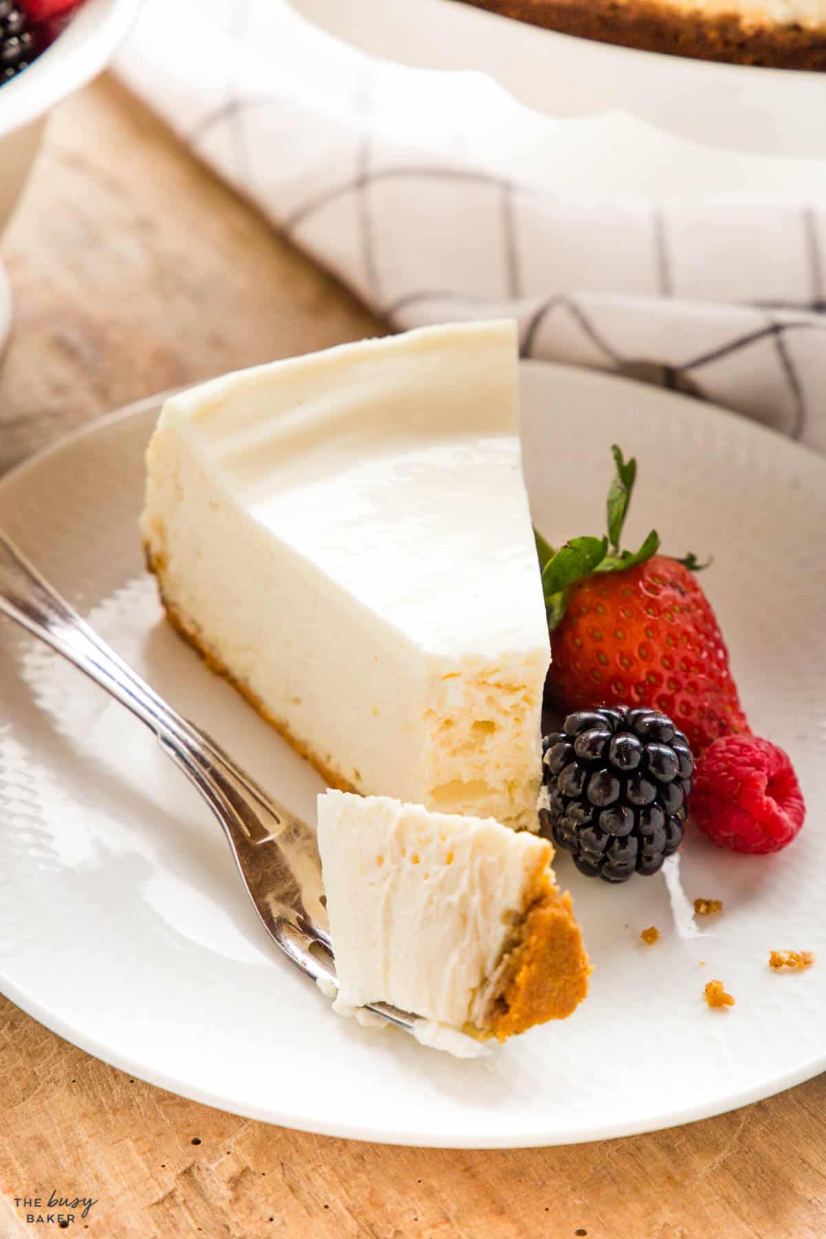 slice of new york cheesecake on a plate with a fork and berries