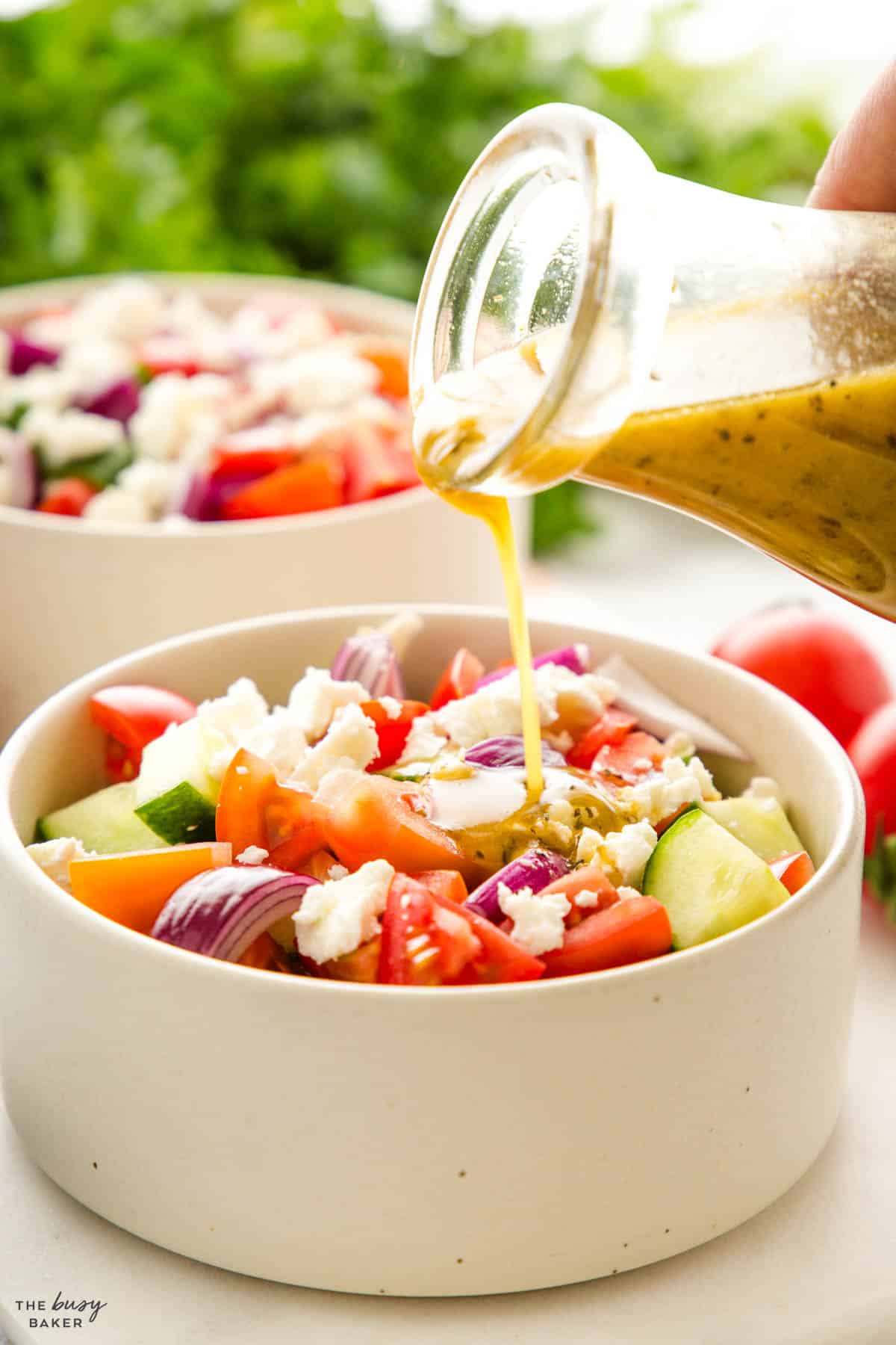 Greek salad dressing being poured over Greek salad