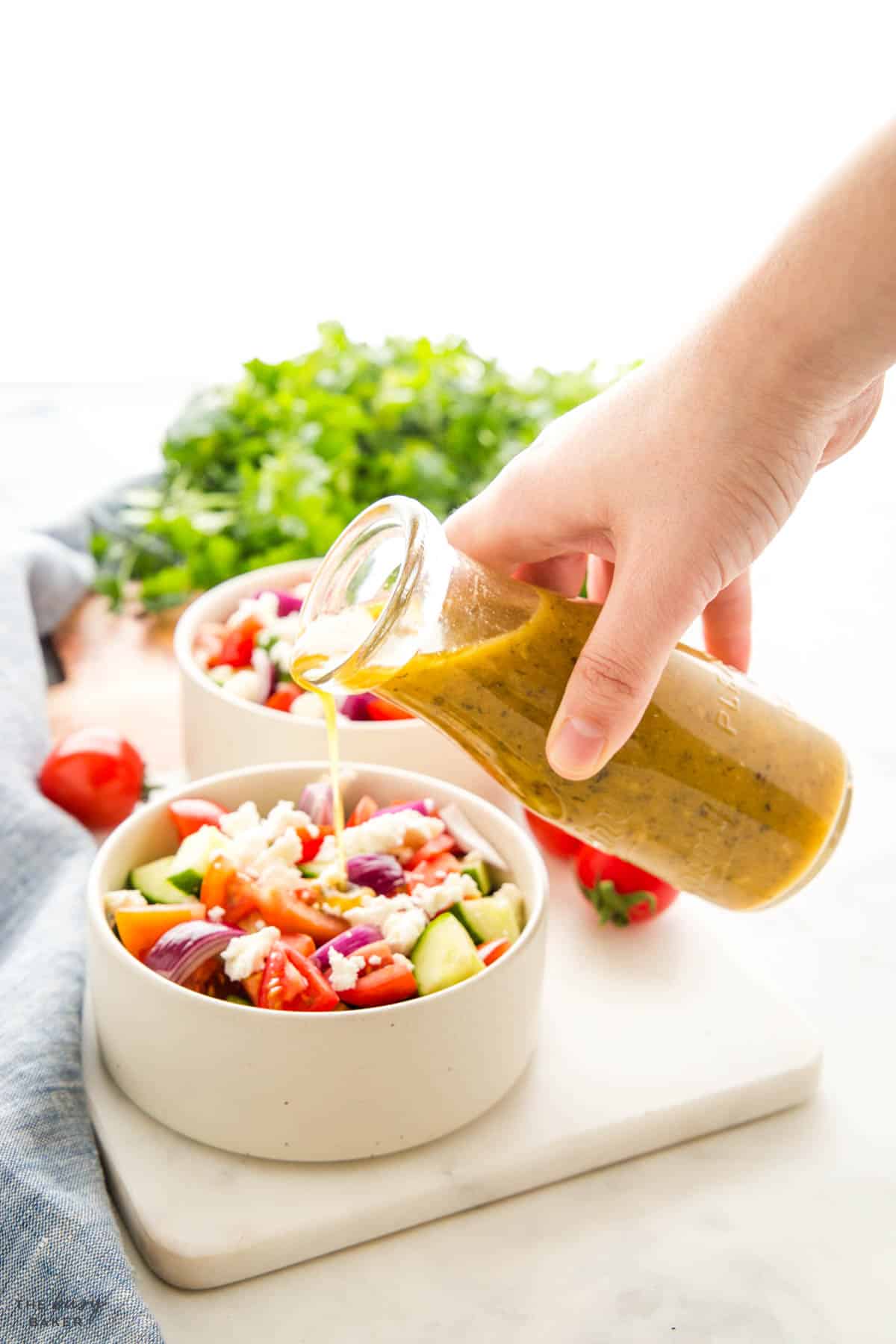 Greek Dressing being poured over a Greek salad 