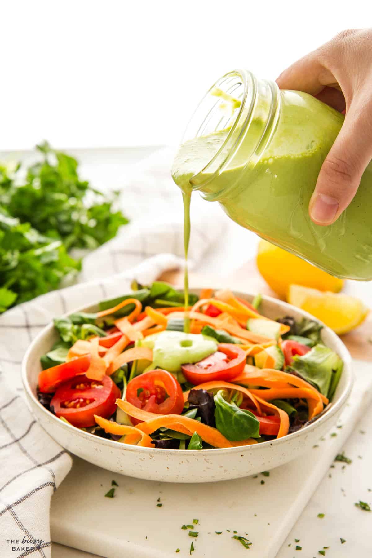 pouring Green Goddess dressing over a salad
